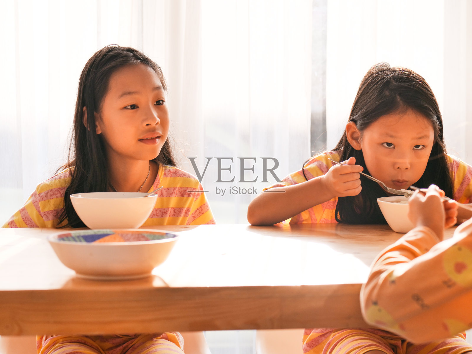 可爱的亚洲女孩在家里窗户附近一起吃米汤早餐。照片摄影图片