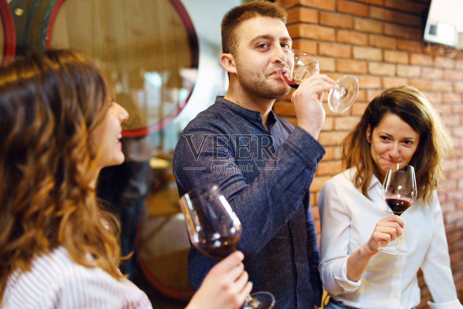 白人朋友两个姐妹或女朋友和男朋友的朋友站在桌边的餐厅或酒庄拿着红酒杯喝酒庆祝穿着衬衫正面观照片摄影图片