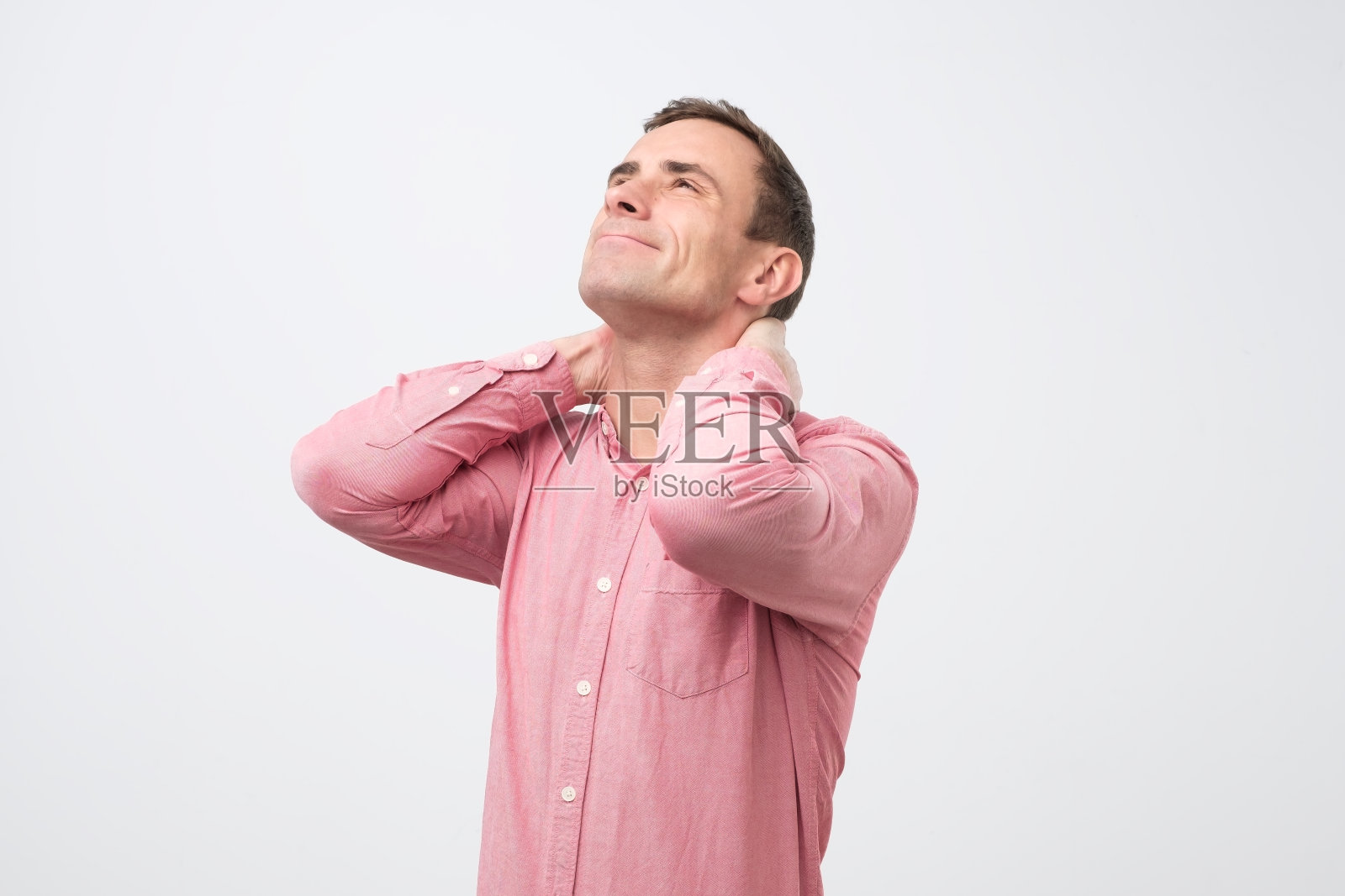 穿着粉红色衬衫的成年男子因骨软骨症、疝或痉挛而颈部疼痛照片摄影图片