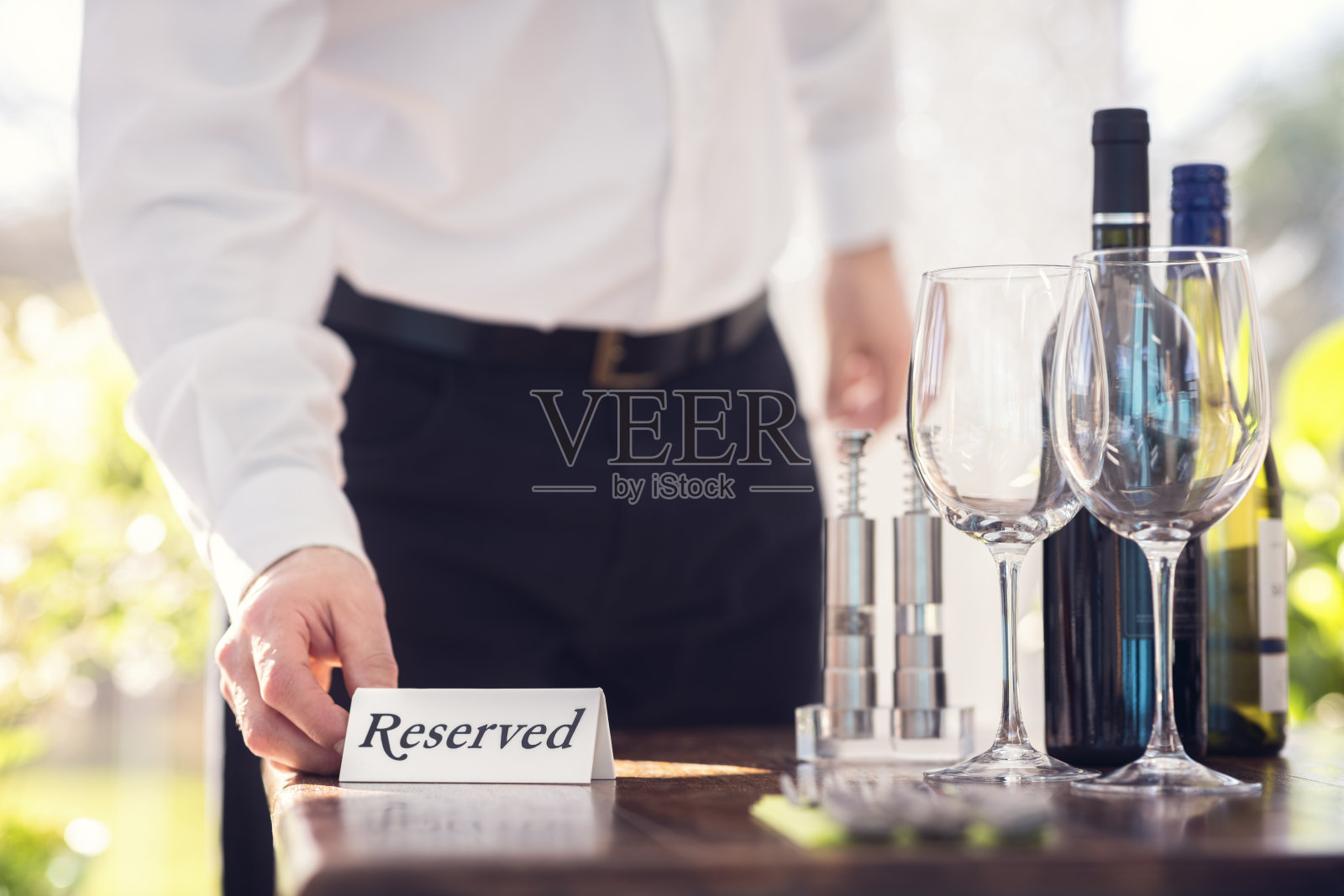 餐厅服务员放置一个预留的桌子标志与位置设置和酒杯准备一个聚会照片摄影图片