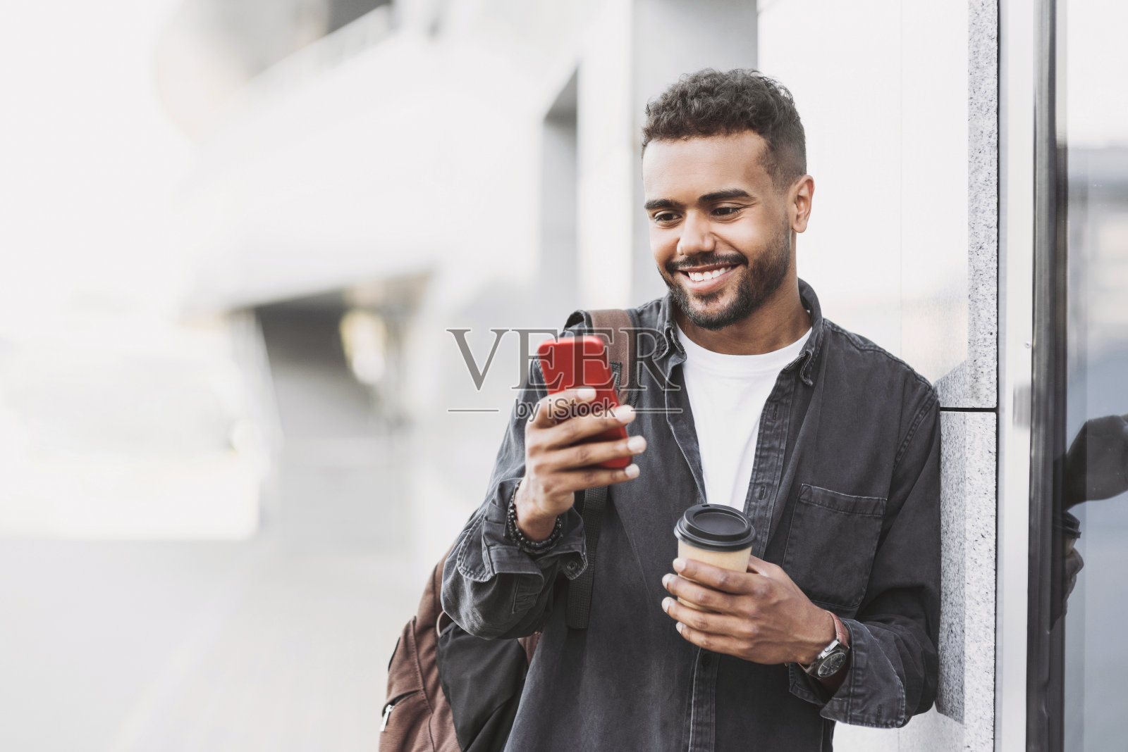 一个快乐的年轻人在城市里使用智能手机照片摄影图片