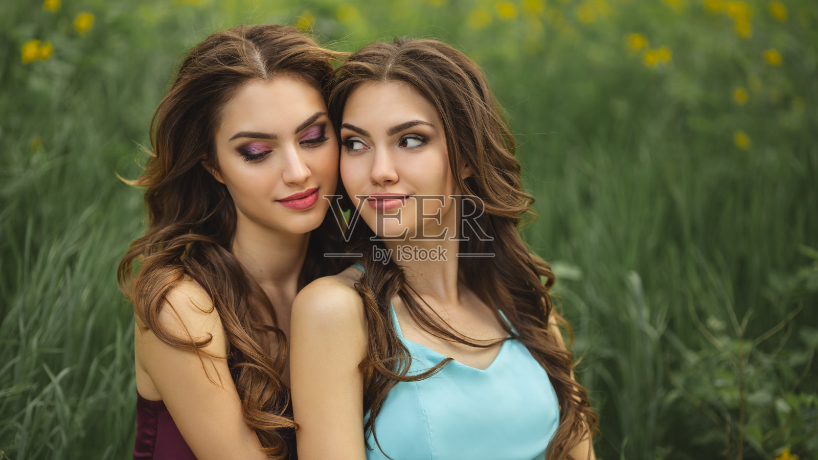 两个女人的时尚肖像照片，在大自然的绿草地上照片摄影图片