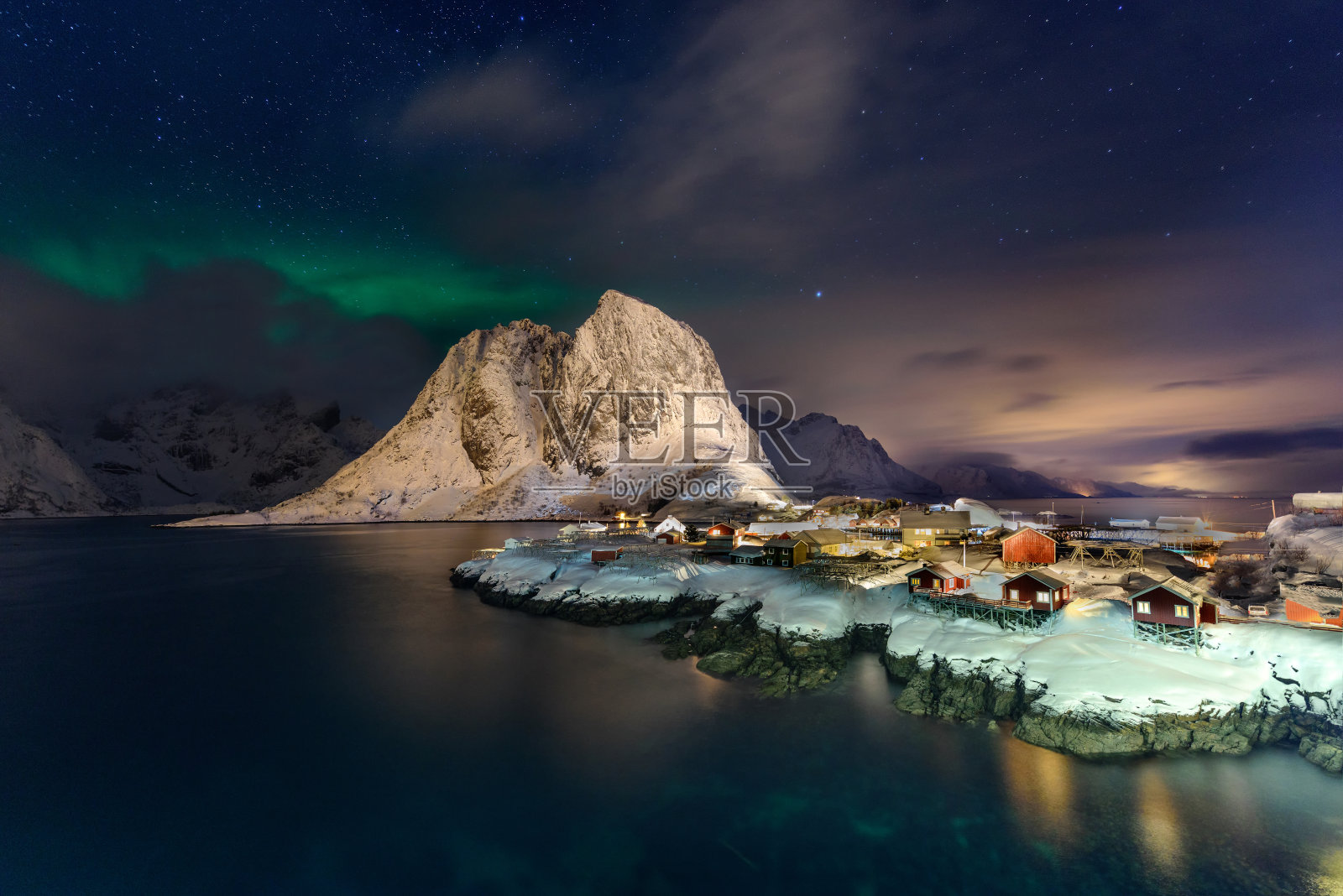 挪威罗浮敦岛哈姆诺伊美丽的北极光。北极光笼罩着这个有着传统红色小屋的小渔村。雄伟的绿色夜空。照片摄影图片