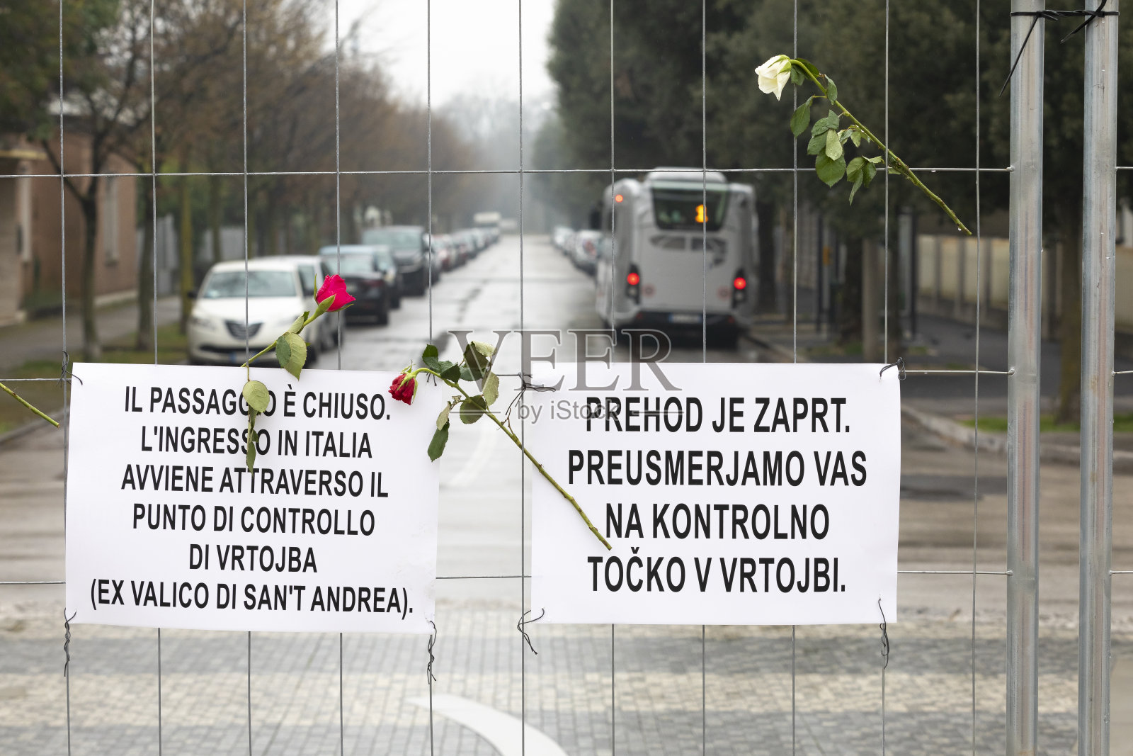 意大利/斯洛文尼亚边境上的栅栏，手里拿着鲜花，并在上面签上了重定向的说明。照片摄影图片