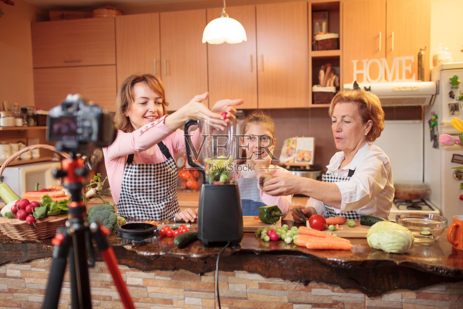 快乐的母亲，女儿和孙女录制视频说明准备健康的素食食品照片摄影图片