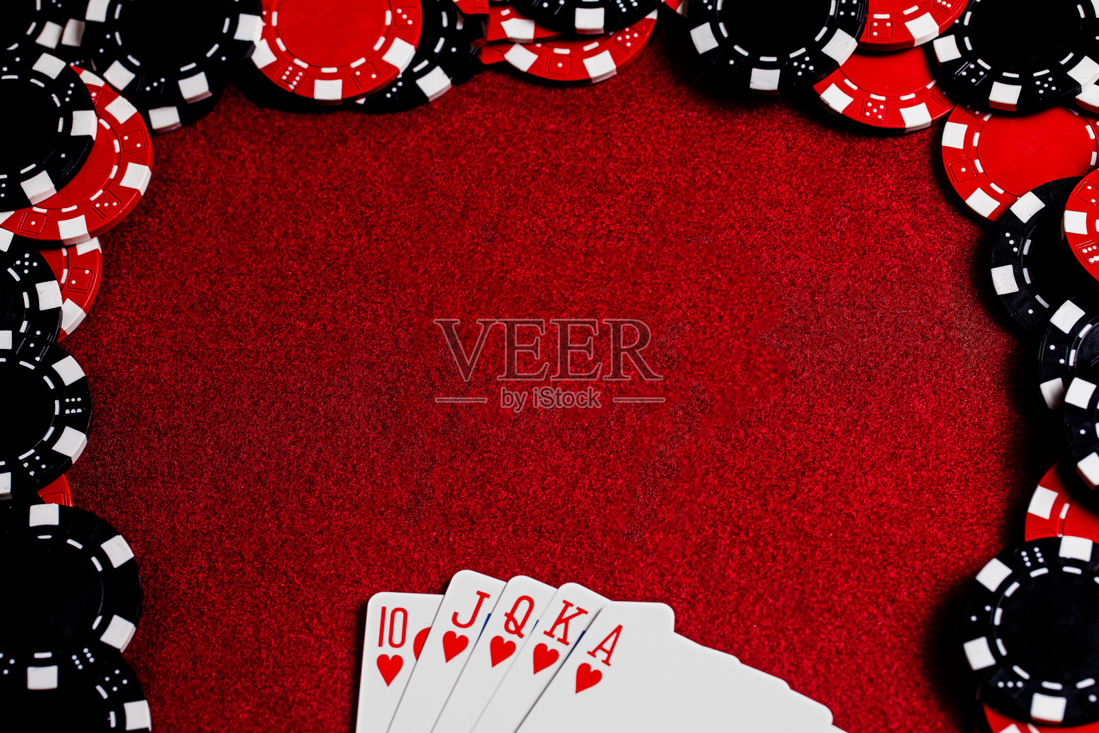 一个皇家红心同心圆扇形在框架的底部，和一个大空间的复制在深红色毛毡桌子表面的中心被红色和黑色粘土扑克筹码包围。高对比度和拍摄副本。照片摄影图片