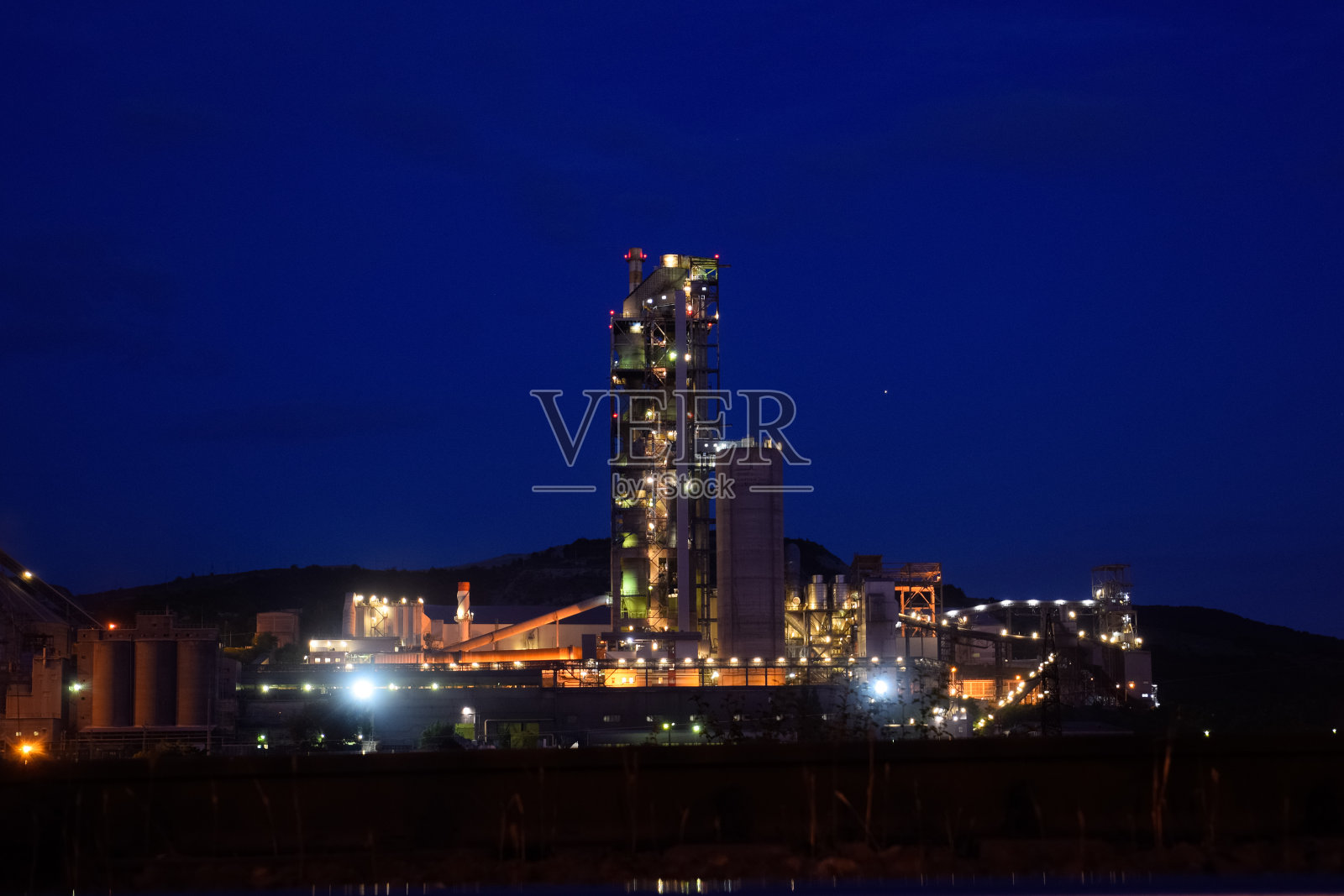 晚上建一座水泥厂，一盏灯的灯光照亮了工厂。工业设施。照片摄影图片