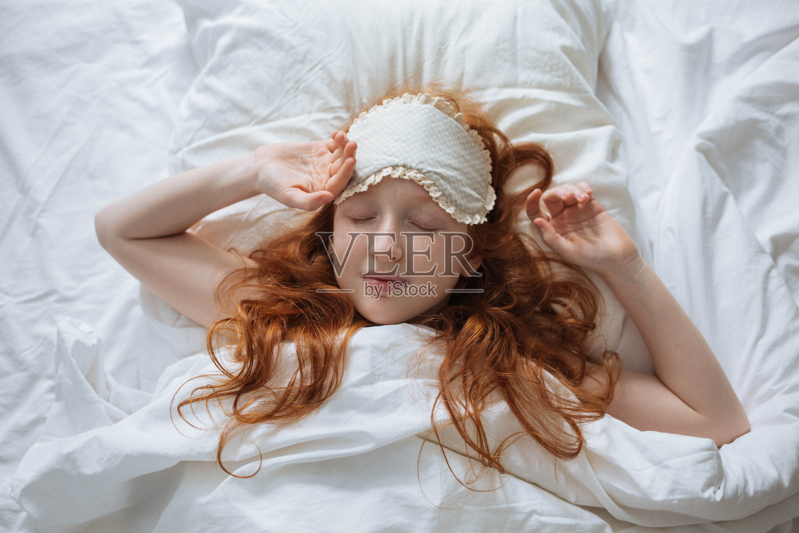 红头发的小女孩早上在她的婴儿床里醒来照片摄影图片