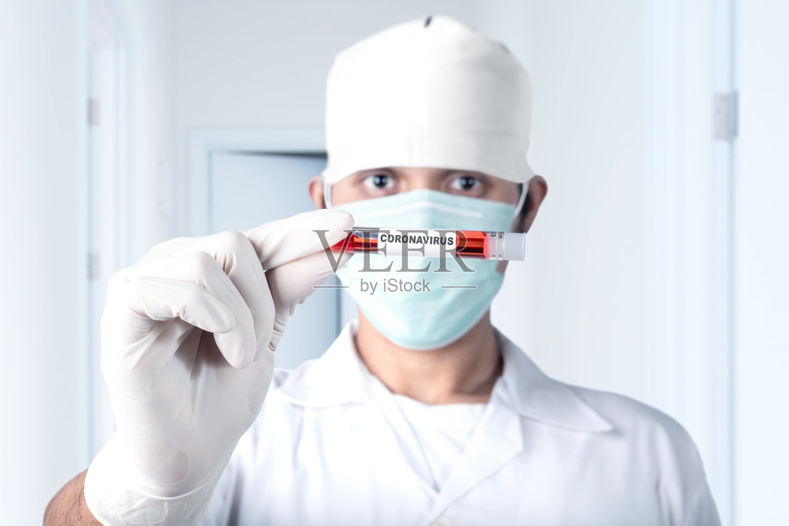 一名亚洲医生戴着流感口罩和防护手套，拿着一个装有冠状病毒血样的试管照片摄影图片