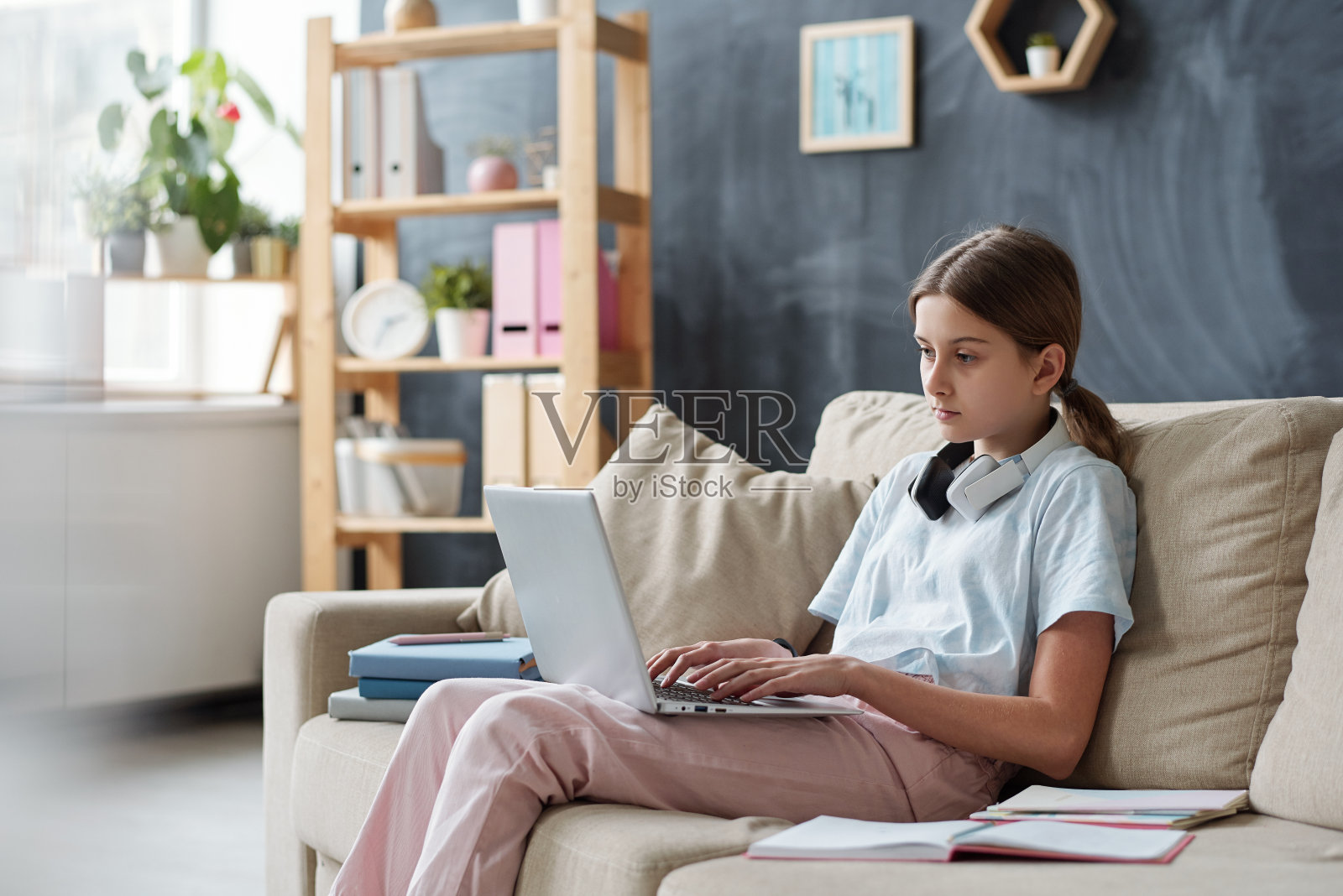 一个严肃的青少年坐在沙发上用笔记本电脑上网照片摄影图片