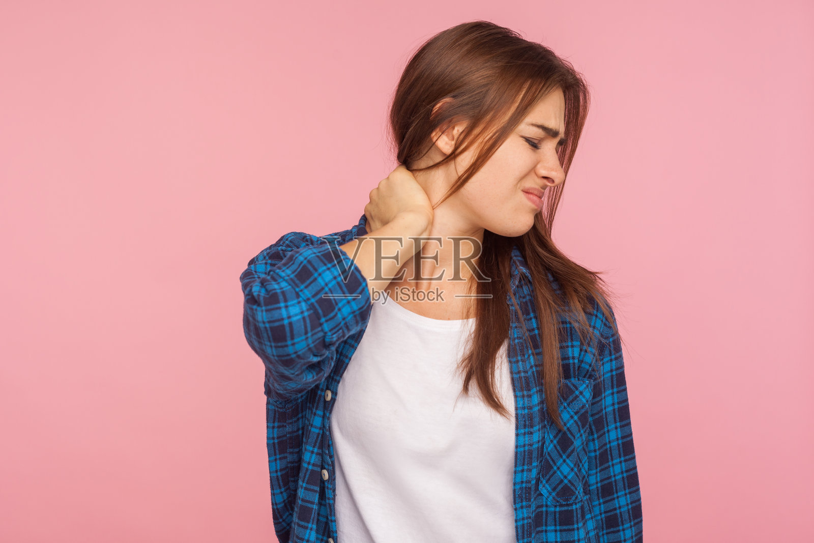 肖像疲惫不健康的妇女在格子衬衫按摩疼痛的颈部，遭受肌肉劳损照片摄影图片
