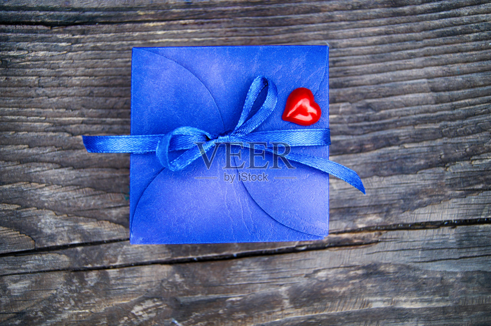 礼物盒的蓝色与一个弓和一个心在一个木制的背景照片摄影图片