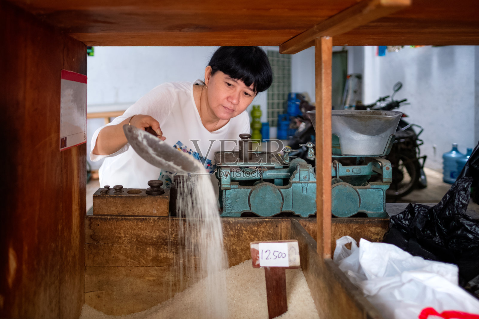 亚洲印尼妇女在当地一个小型家庭经营的商店里卖大米，当地称为warung。有选择性的重点。照片摄影图片