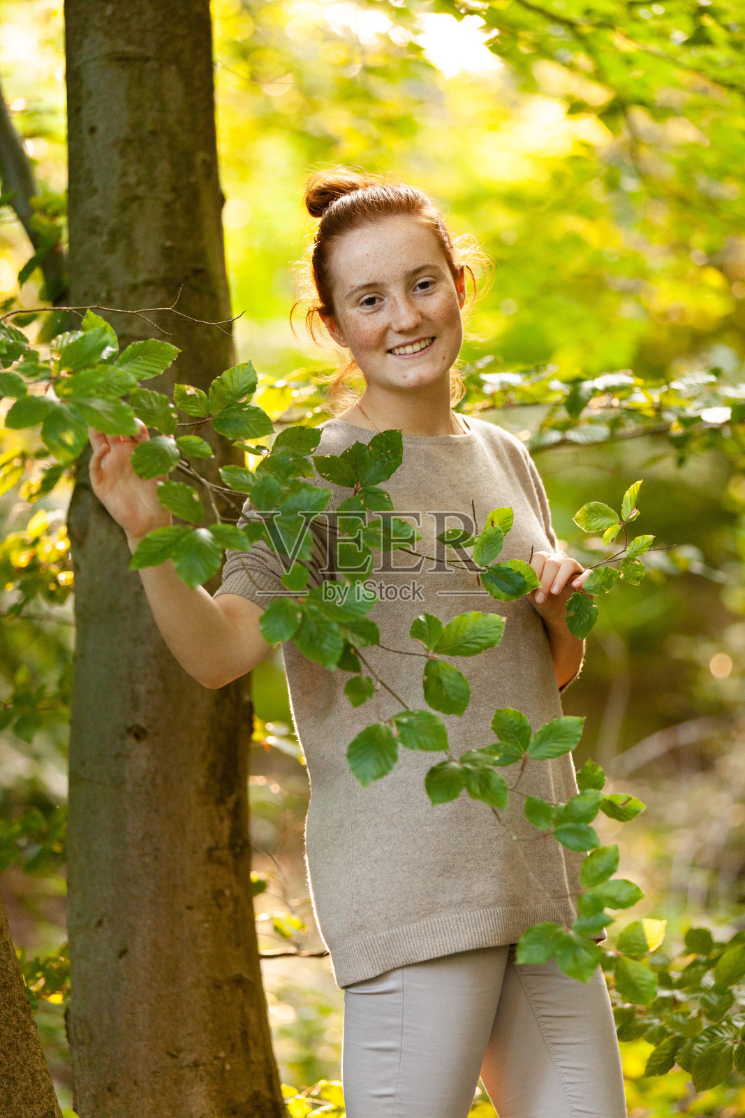 红发女孩在森林里，在一棵树旁摆造型照片摄影图片