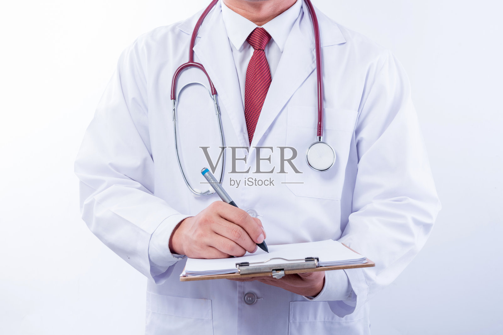 身穿制服，带听诊器的医生站在白色背景上照片摄影图片