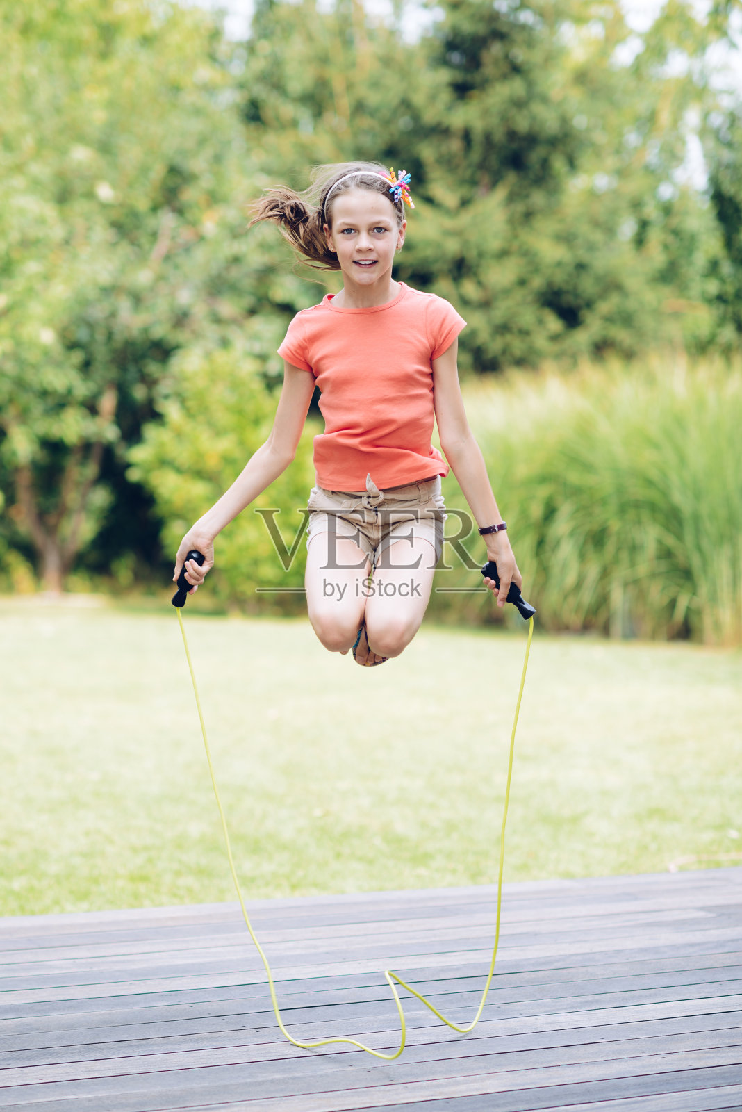 笑着跳绳的少女在花园里的露台上照片摄影图片