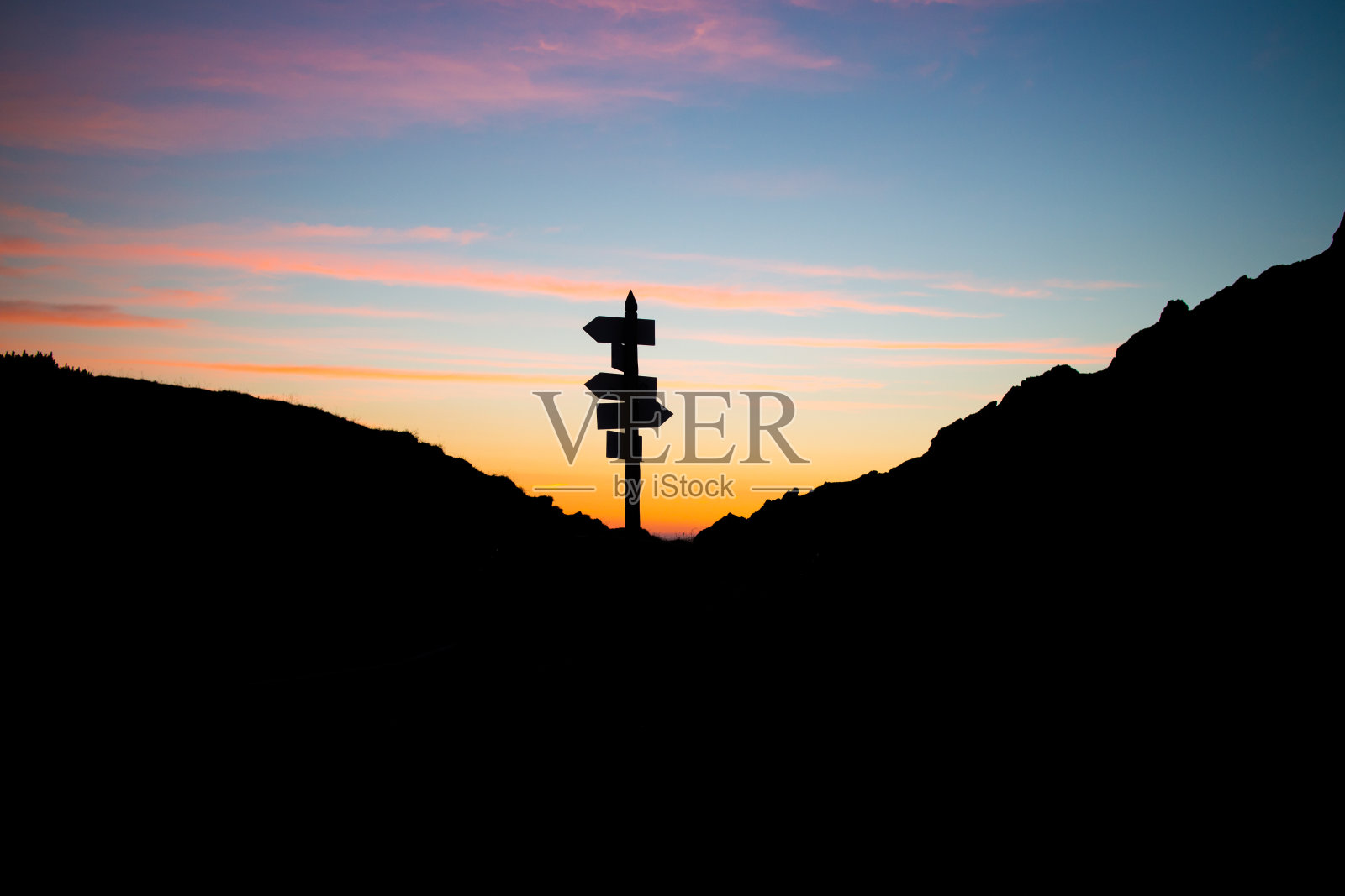 在明亮的日落天空下，山顶上的一个路标的影子照片摄影图片