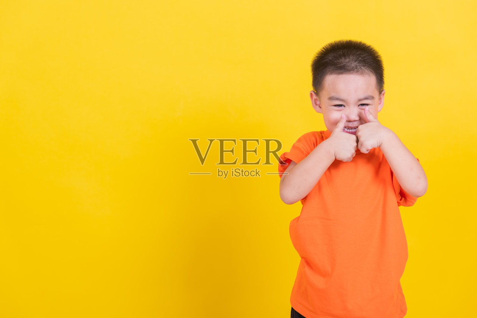 亚洲泰国快乐的肖像可爱的小男孩快乐的小男孩穿着橘黄色的t恤看着相机，工作室拍摄孤立照片摄影图片