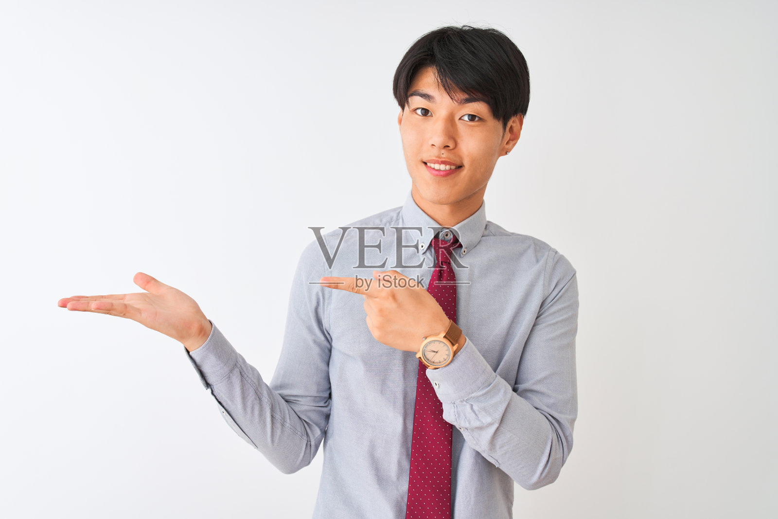 中国商人戴着优雅的领带，站在孤立的白色背景下惊讶地微笑着，同时用手指着镜头。照片摄影图片