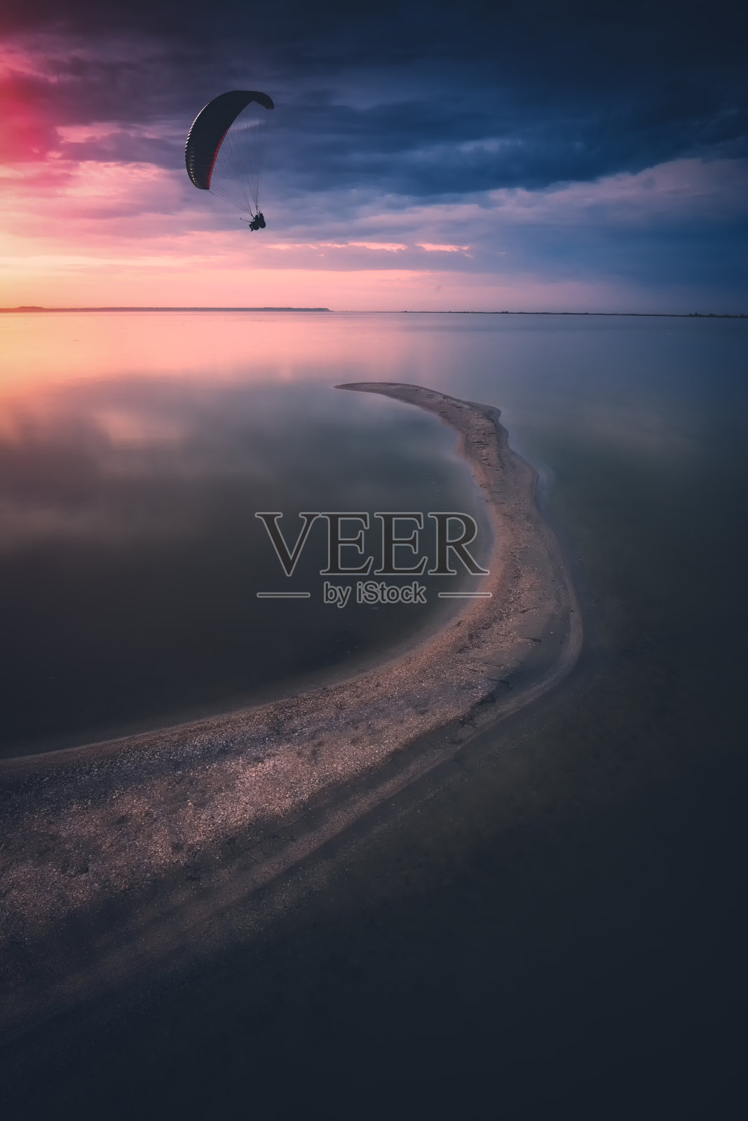 滑翔伞的剪影在明亮的彩色日落的背景下飞过海面照片摄影图片