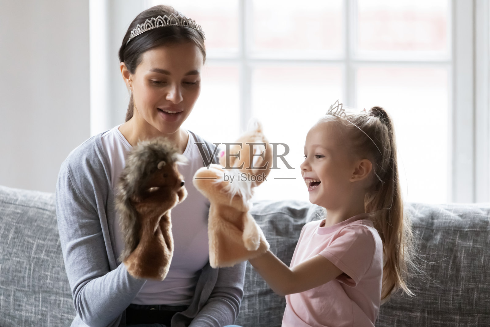 快乐的小女孩戴着皇冠和保姆玩手玩具。照片摄影图片