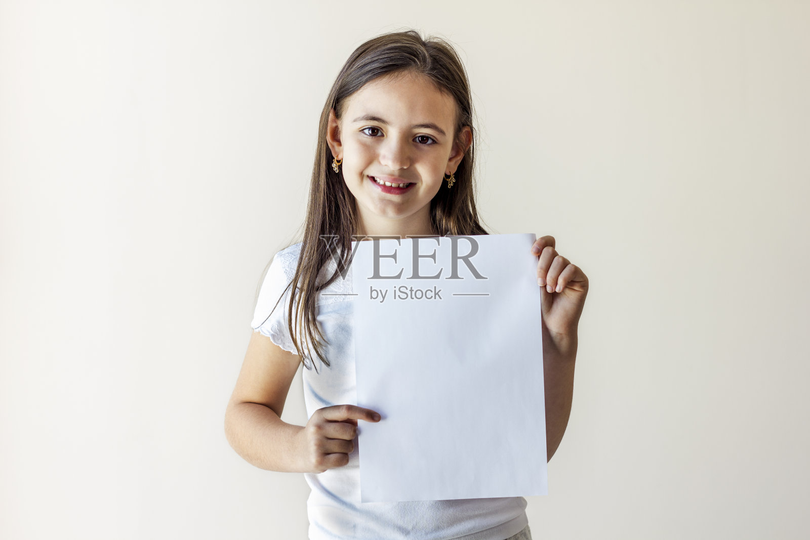年轻的menina拿着一张白纸。快乐可爱的孩子抱着空空白孤立在白色的背景上。拿着黑板的孩子。本空间照片摄影图片