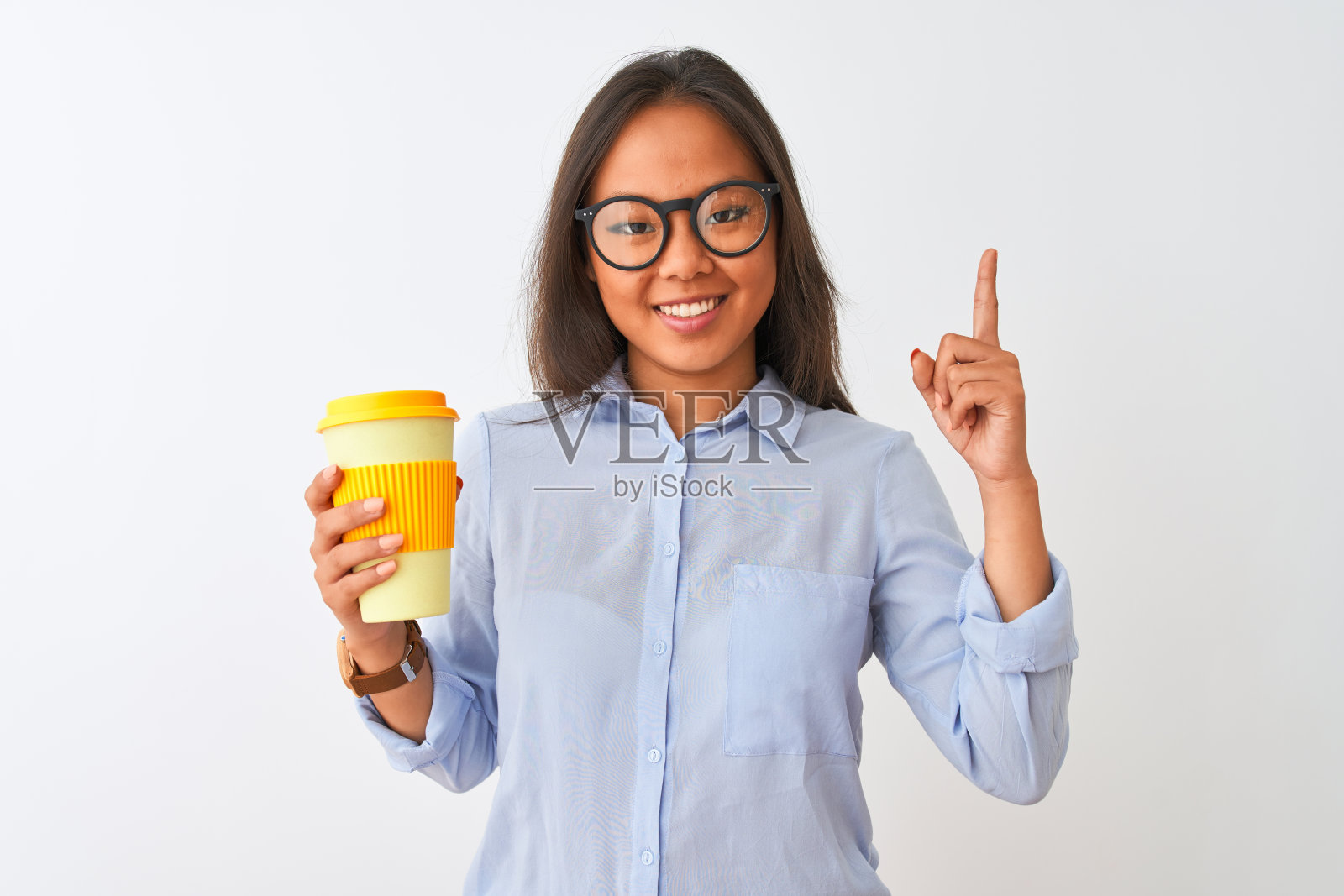 一名戴着眼镜的年轻中国女子在孤立的白色背景下端着一杯咖啡，惊讶地提出了一个想法或问题，开心地指着对方的脸，第一照片摄影图片