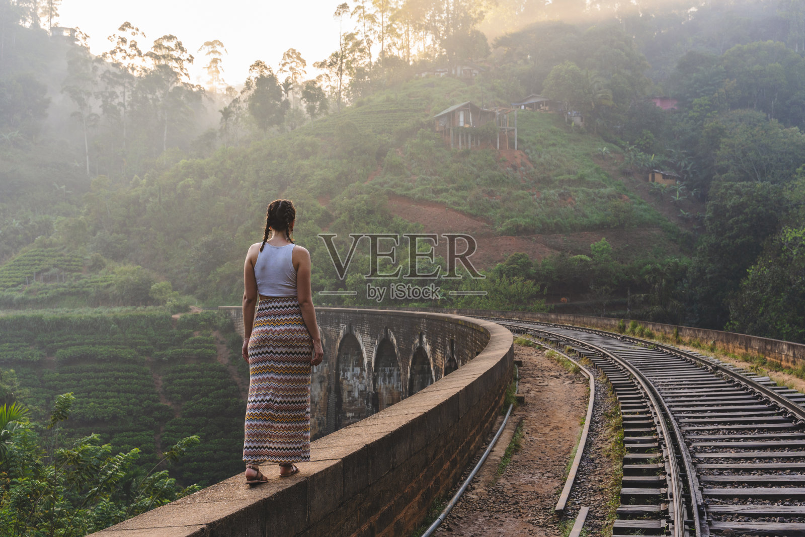 斯里兰卡德莫达拉著名的九拱桥上的年轻女子在日出时行走照片摄影图片
