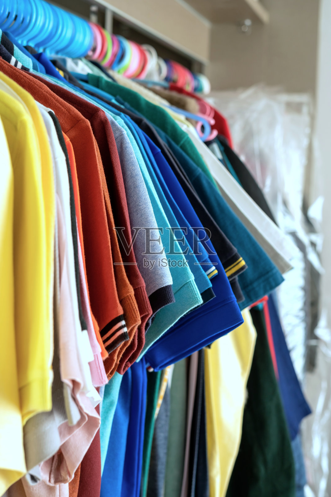 各种色彩鲜艳的衣服整齐地挂在衣柜上照片摄影图片