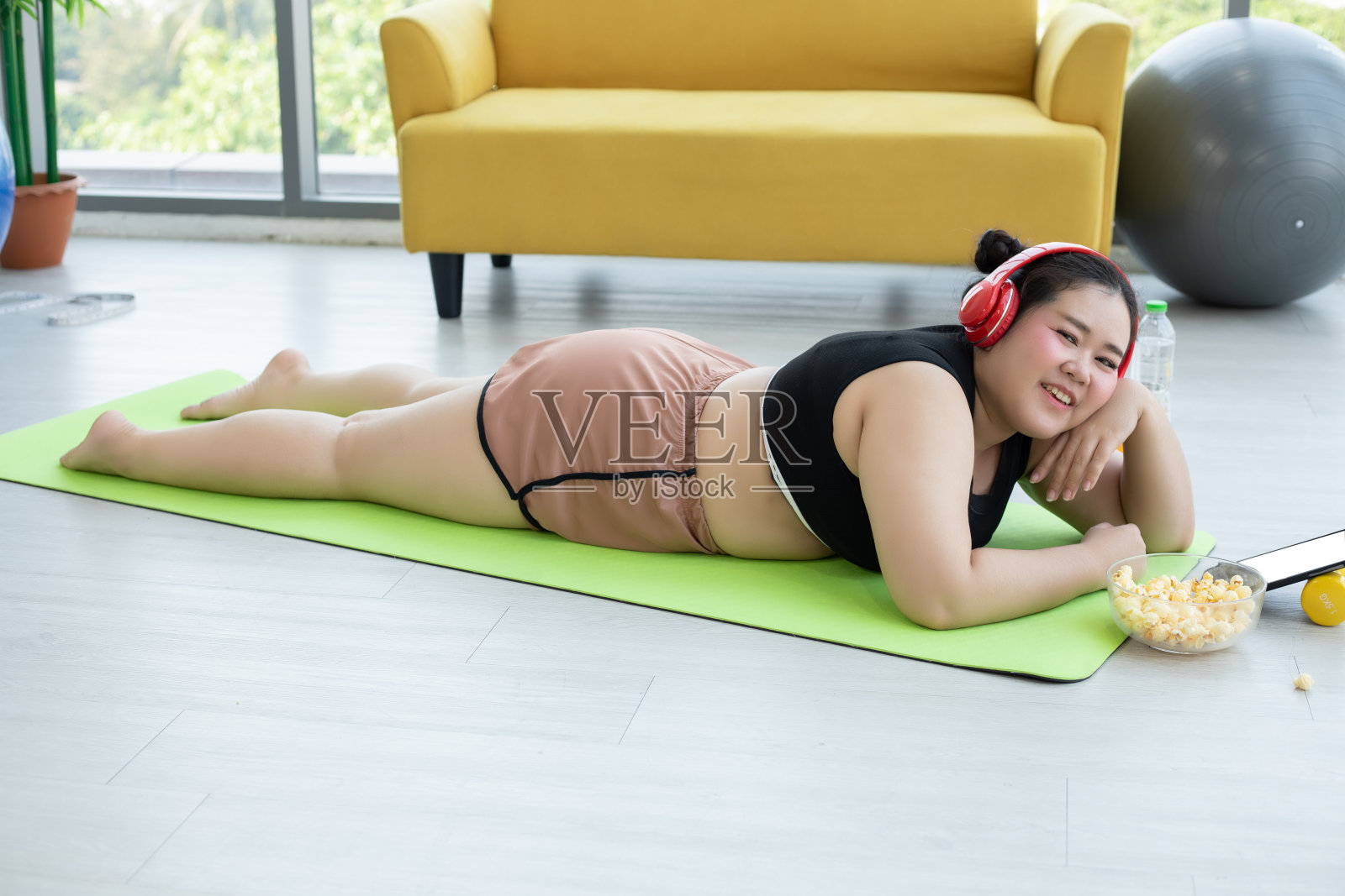 亚洲女性使用平板电脑和。戴着耳机听音乐，她在家锻炼，亚洲女孩喜欢吃食物照片摄影图片