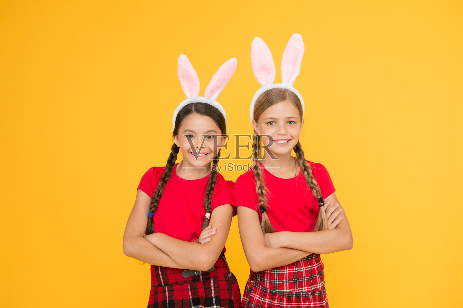 兔子的团队。娱乐和事件概念。春天的假期。孩子们戴着兔子兔耳朵。家人和姐妹。小女生的校服和长兔子耳朵。复活节的传统游戏照片摄影图片