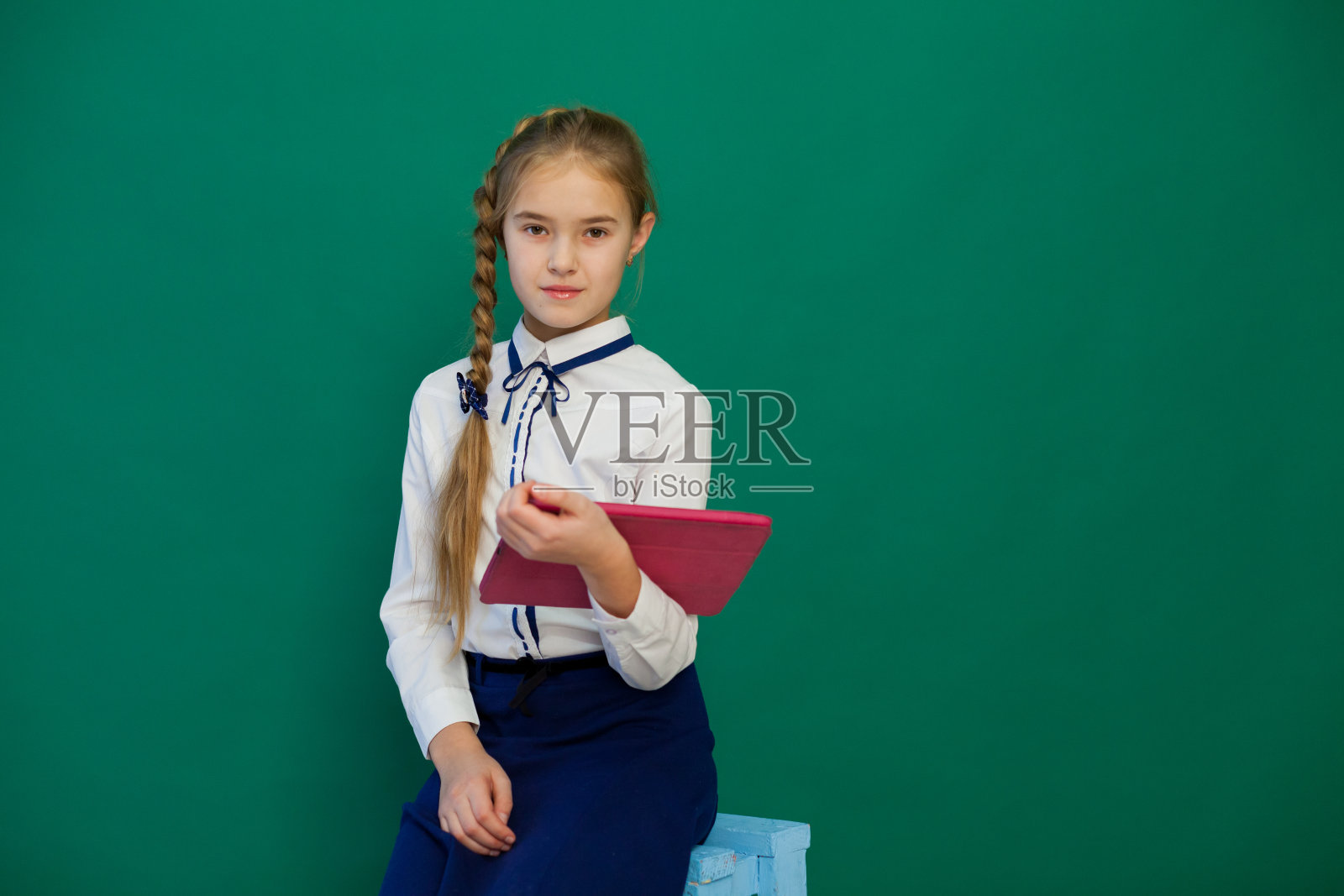 一个女生拿着平板电脑站在教室的黑板前照片摄影图片