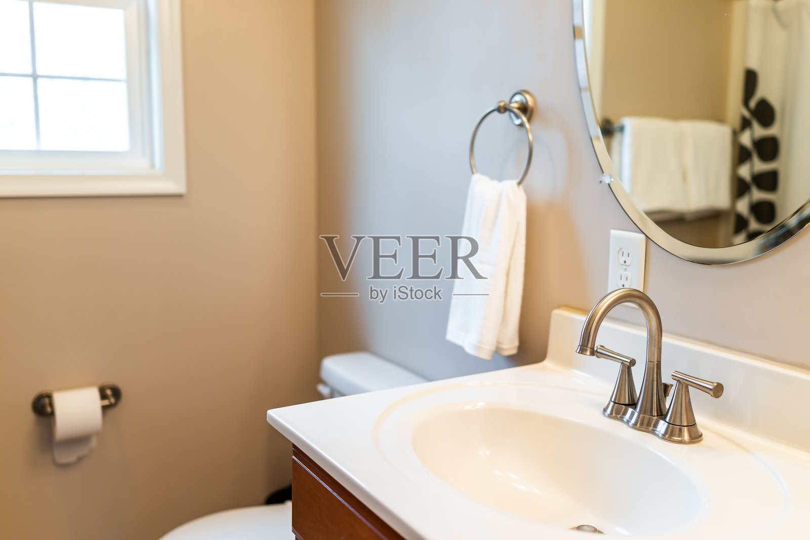 浴室、家庭或公寓的现代白色淡黄色清洁卫生间，有窗户，挂白色毛巾纸和铬水槽和镜子照片摄影图片