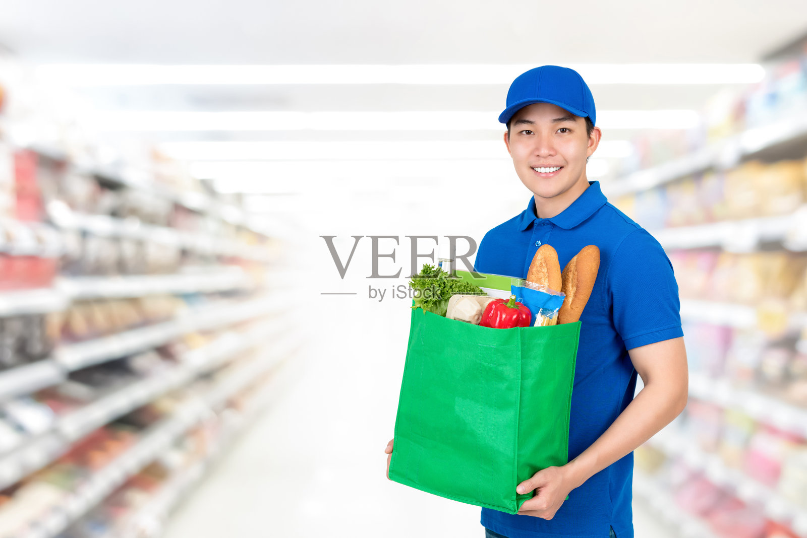 微笑英俊的亚洲男人在超市背景的食品配送服务理念杂货购物袋照片摄影图片