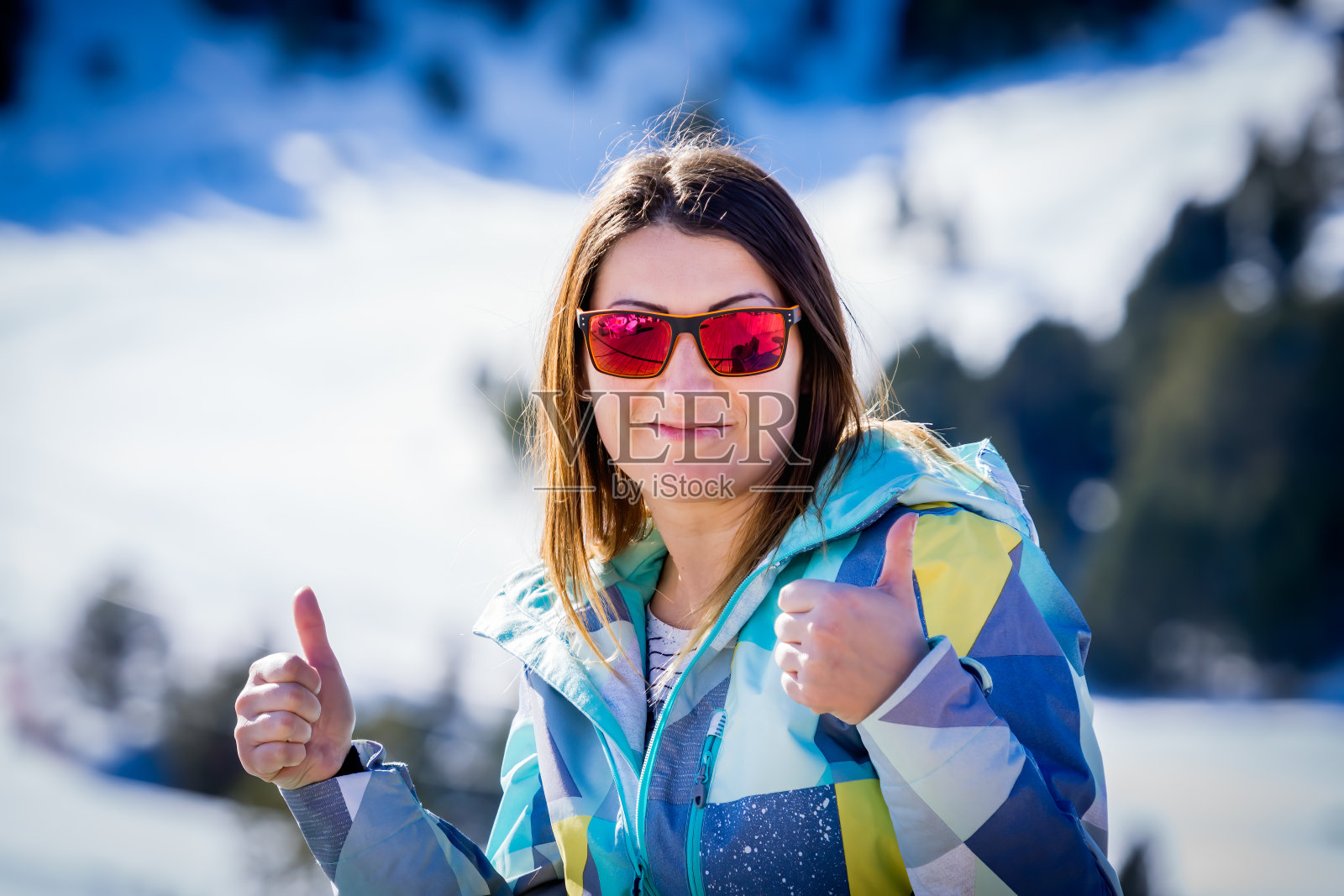 白人妇女的肖像，滑雪显示拇指与冬天的背景。照片摄影图片