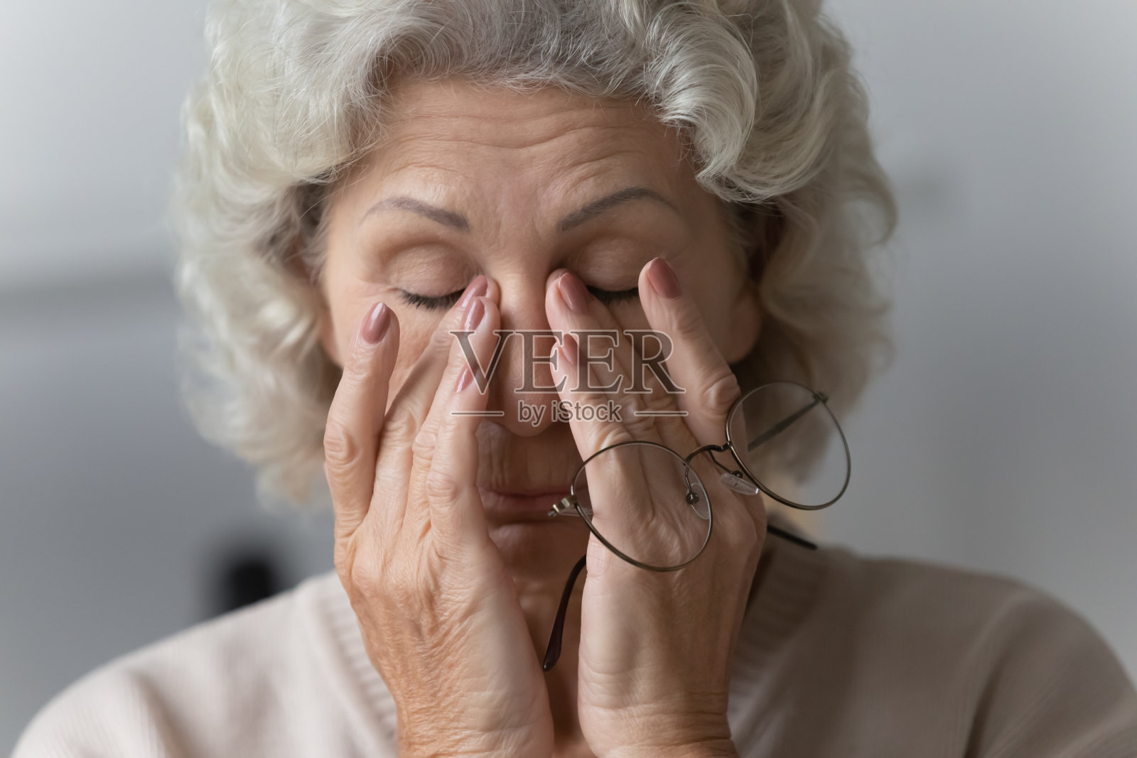 疲惫的成熟女人摘下眼镜后揉鼻梁。照片摄影图片