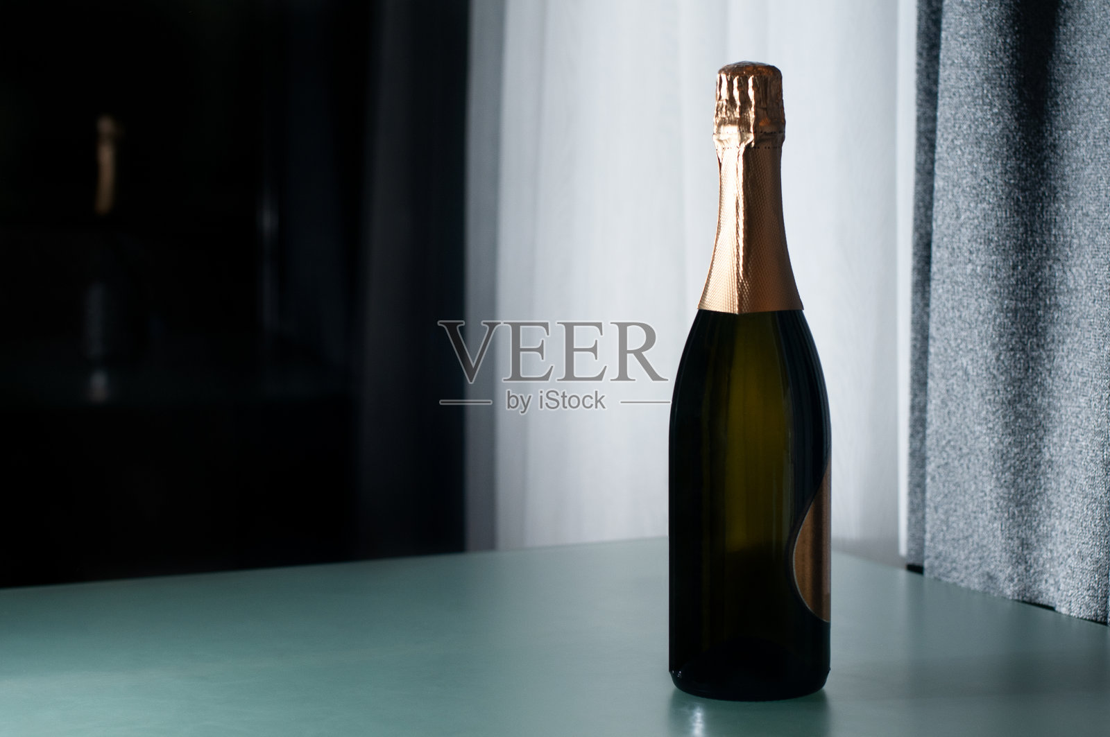 优雅的香槟酒瓶放在玻璃桌上。酒、酒、广告和假日概念。照片摄影图片