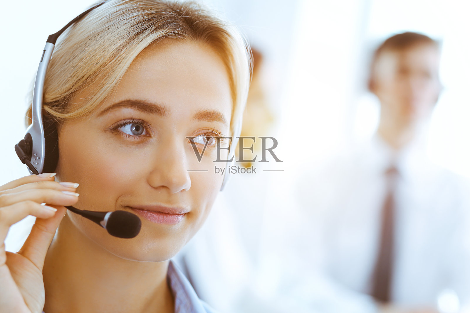 一组不同的电话运营商在阳光办公室工作。带着耳机向客户咨询的帅气女商人。呼叫中心和商务人士的概念照片摄影图片