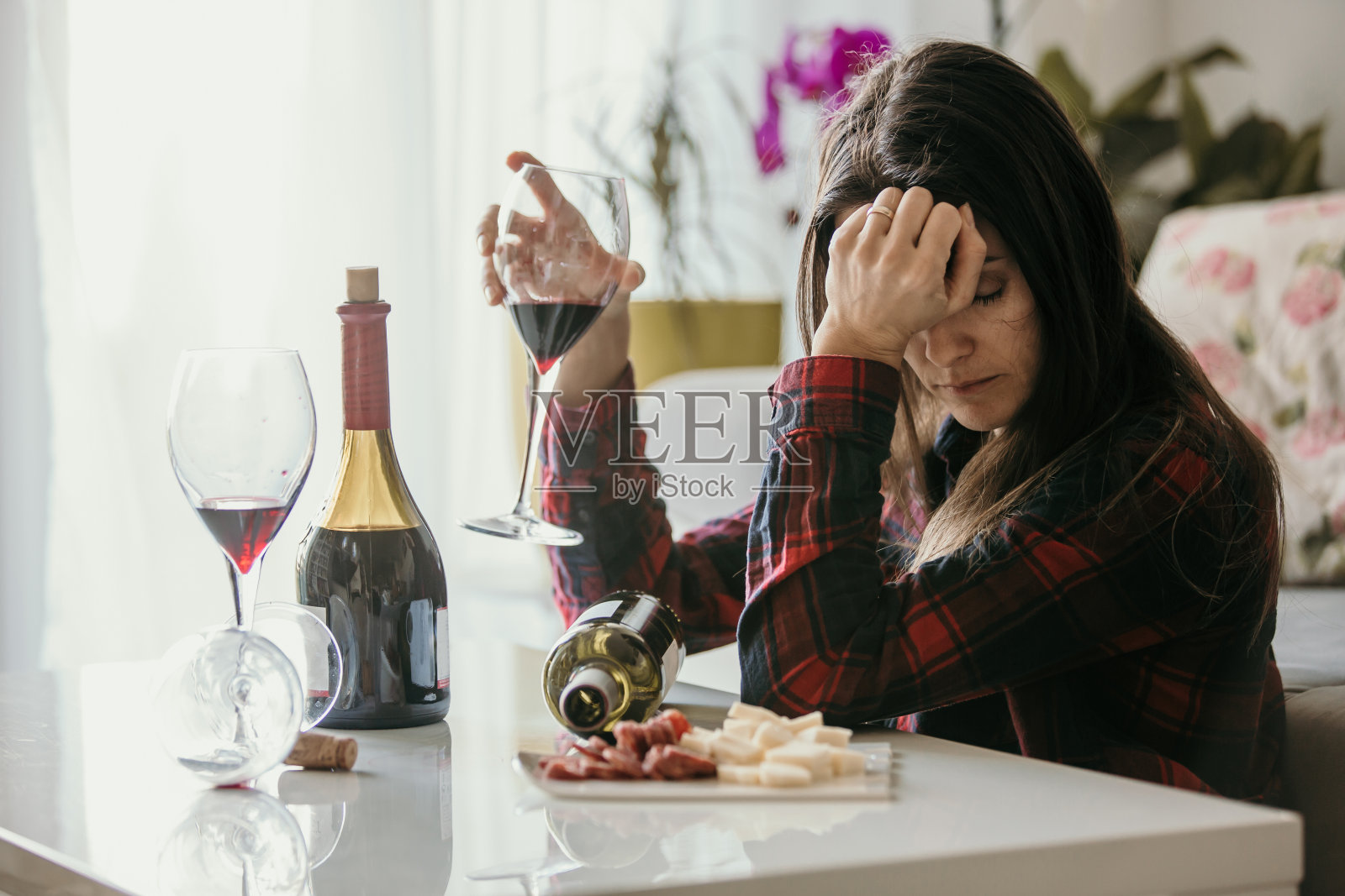 悲伤疲惫的女人，在家里喝酒，独自坐在客厅的地板上照片摄影图片