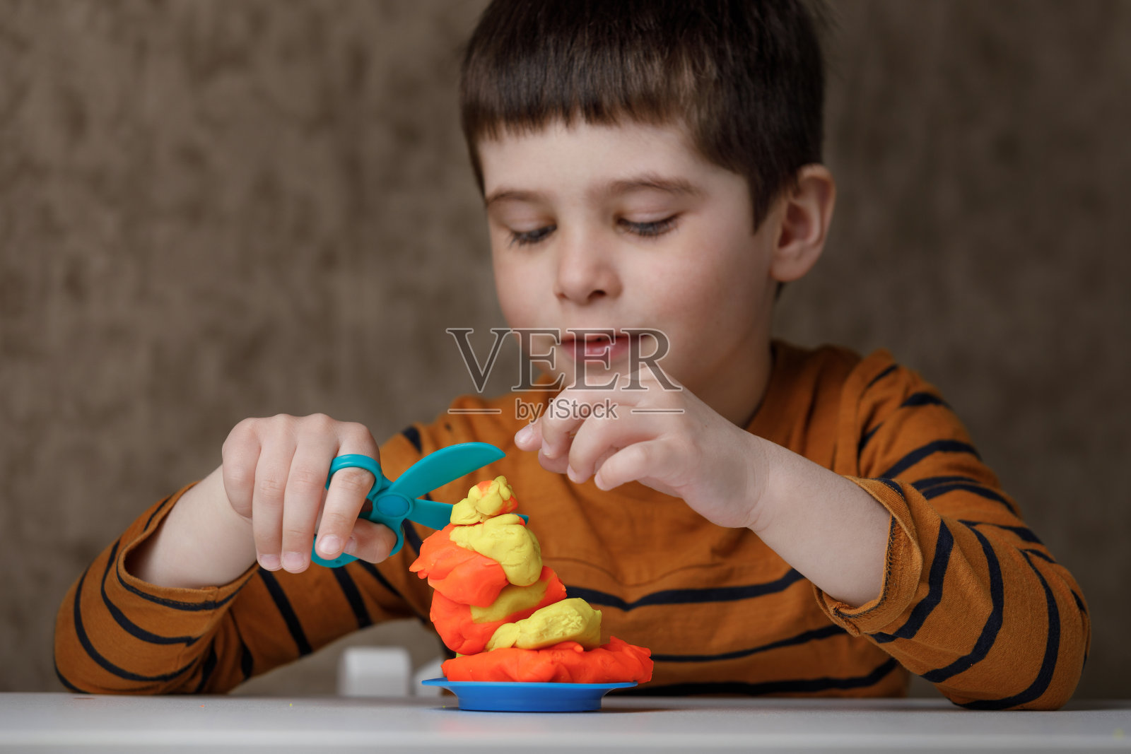 这个男孩雕刻橡皮泥。一个孩子在家玩雕刻。照片摄影图片