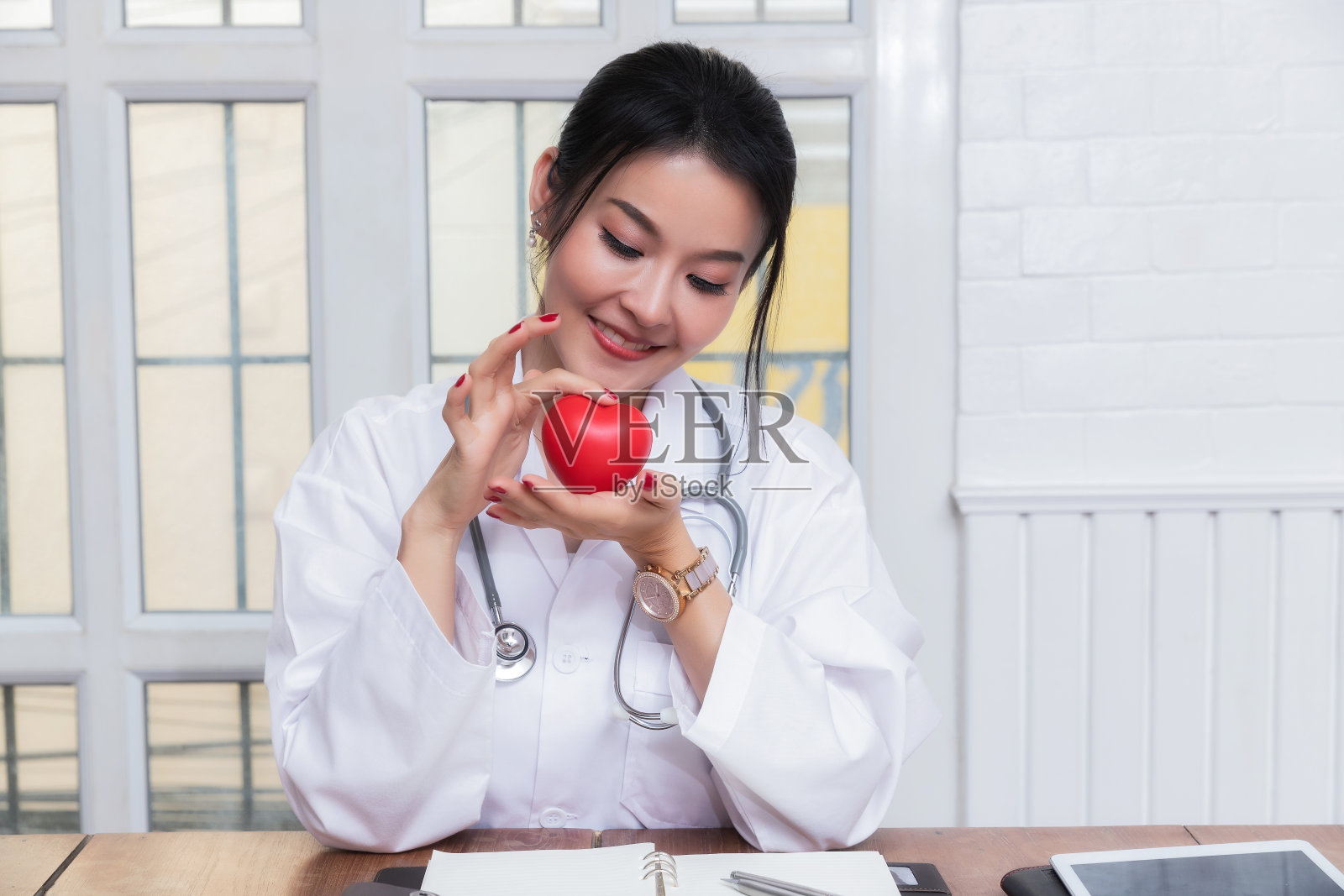 女医生在医院拿着一个红心球。保健和医疗的概念。照片摄影图片