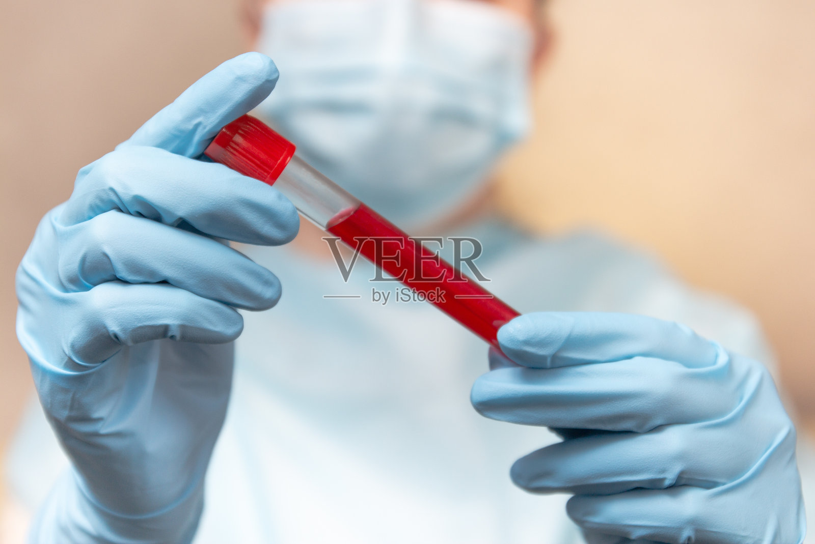 冠状病毒的血液测试。医生穿着防护服，医用口罩和乳胶手套拿着一个血液试管。照片摄影图片