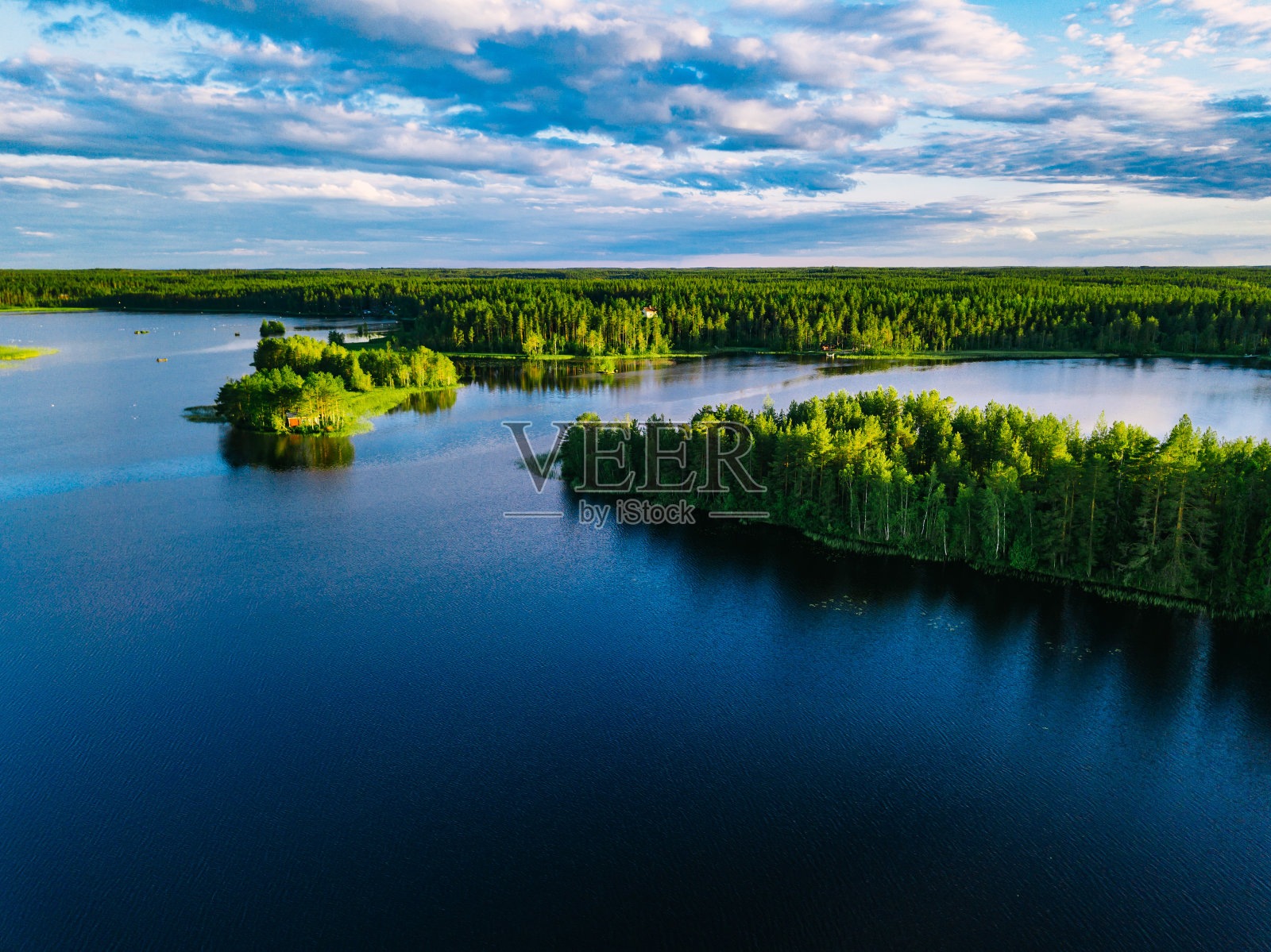 鸟瞰图蓝色的湖泊和绿色的森林在一个阳光明媚的夏天在芬兰。照片摄影图片