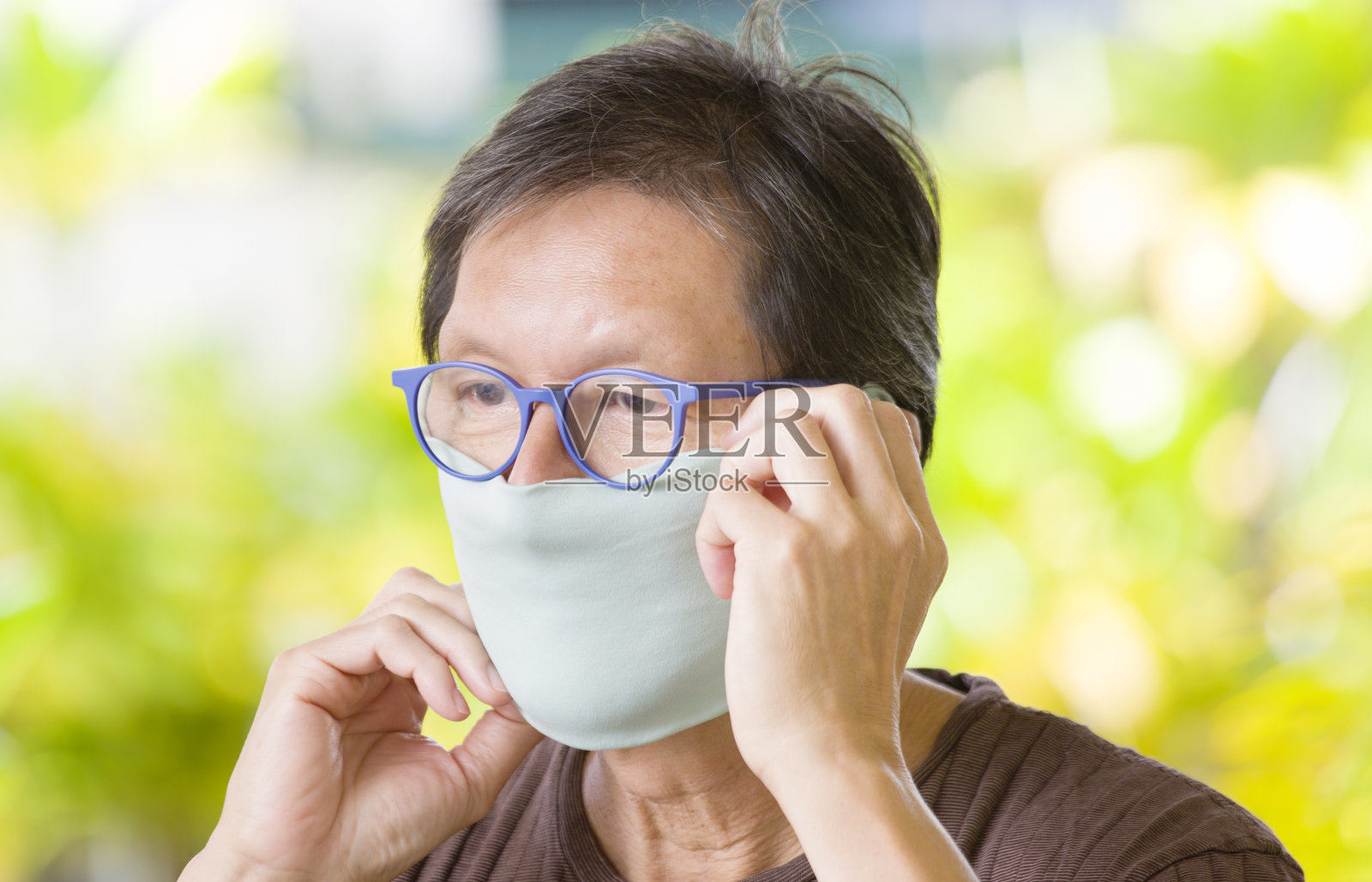 COVID-19户外老人调整自制口罩以保持社交距离照片摄影图片