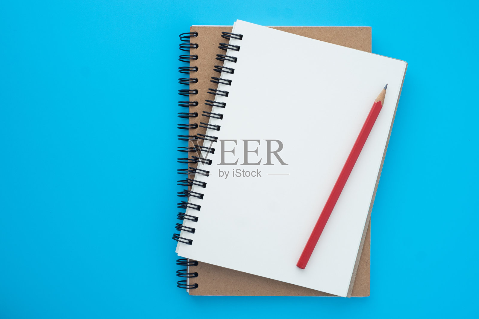 上面的顶视图打开螺旋笔记本和红铅笔孤立在浅蓝色的背景设计一个模型。教育与经营理念。平躺照片摄影图片