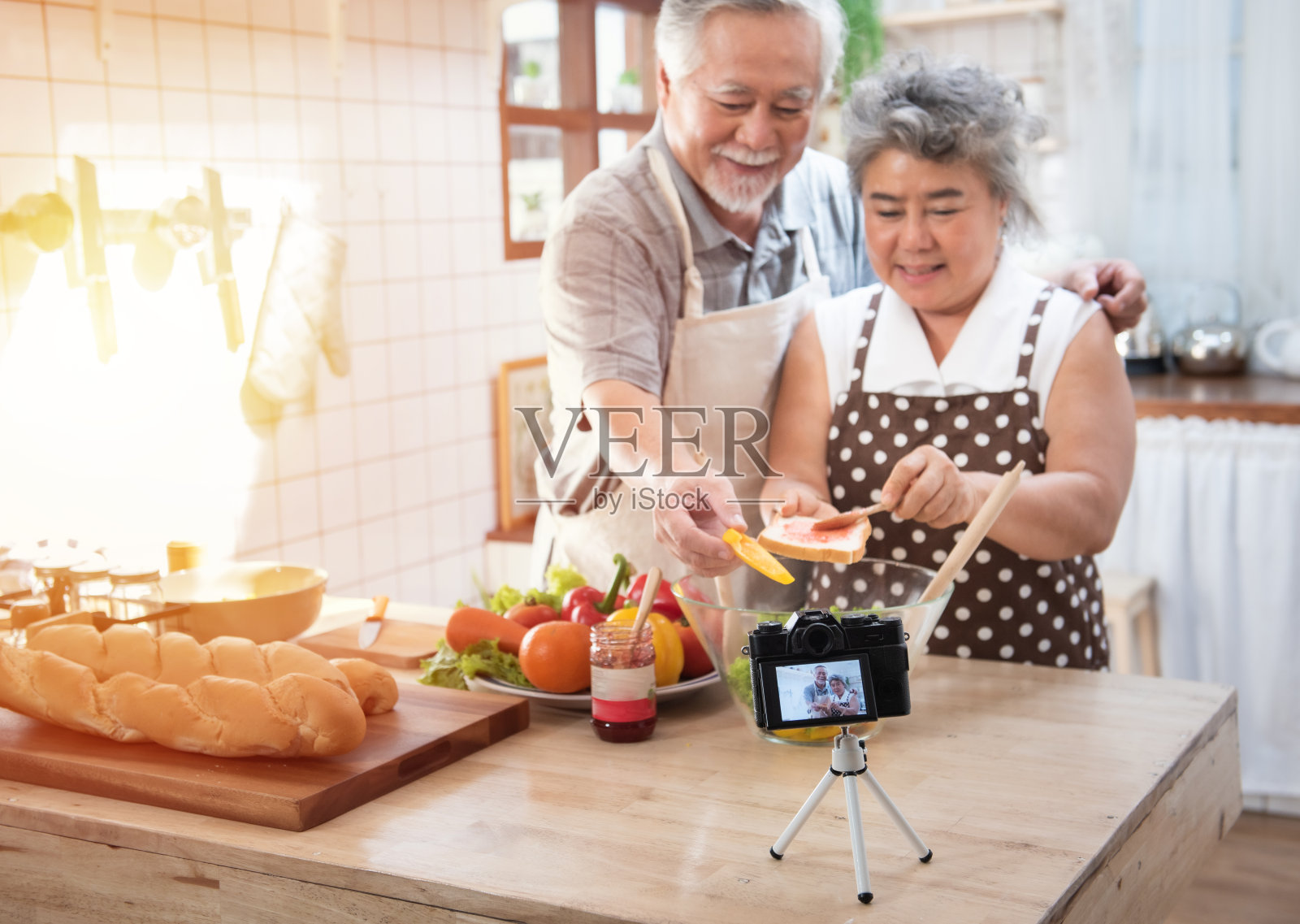 夫妇老亚洲长者幸福生活在家庭厨房。爷爷和奶奶用果酱擦面包。专注于相机。现代生活方式和关系。照片摄影图片