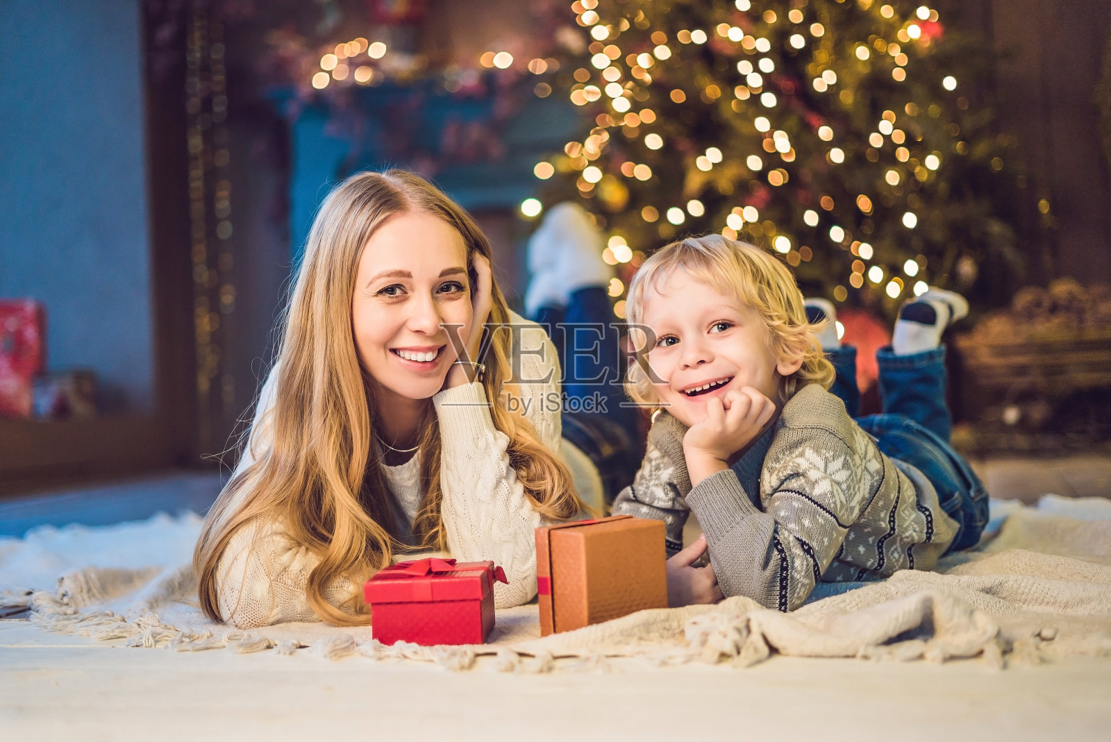 快乐的妈妈和可爱的男孩庆祝圣诞节的肖像。新年假期。幼童和妈妈在节日装饰的房间里的圣诞树和装饰品照片摄影图片