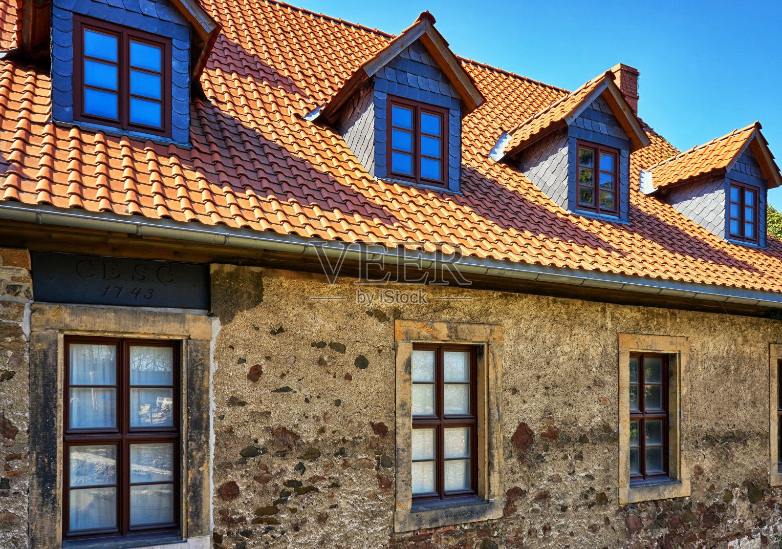 翻新的瓦片屋顶和旧砖墙上的天窗。照片摄影图片