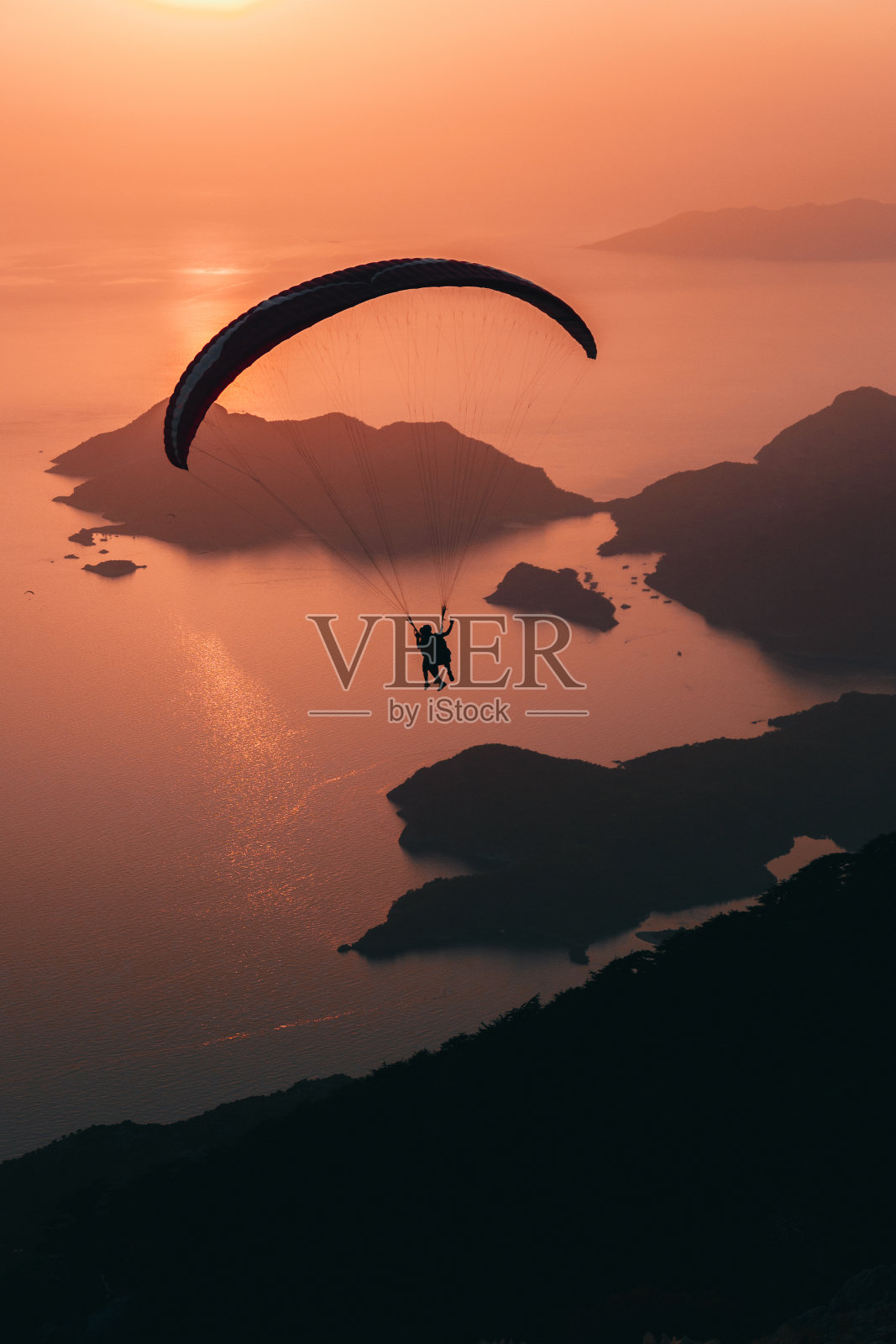 在土耳其Oludeniz的蓝礁湖上，日落时的滑翔伞照片摄影图片
