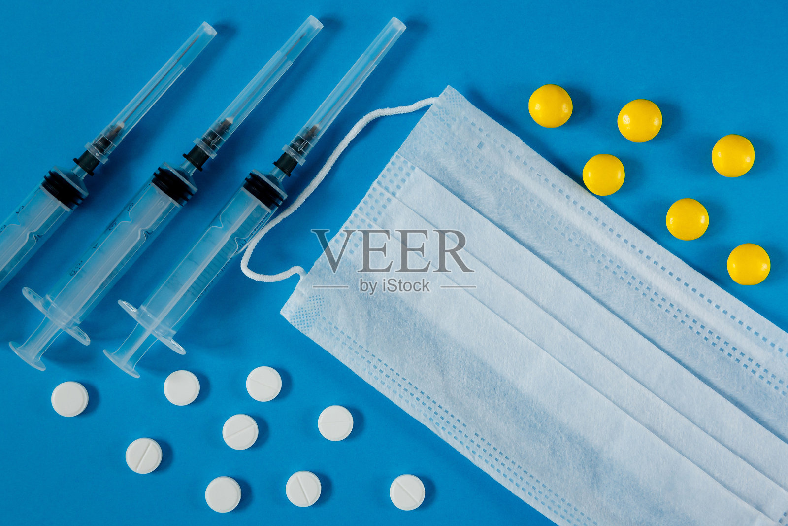 医用口罩，注射器和药丸，蓝色背景照片摄影图片
